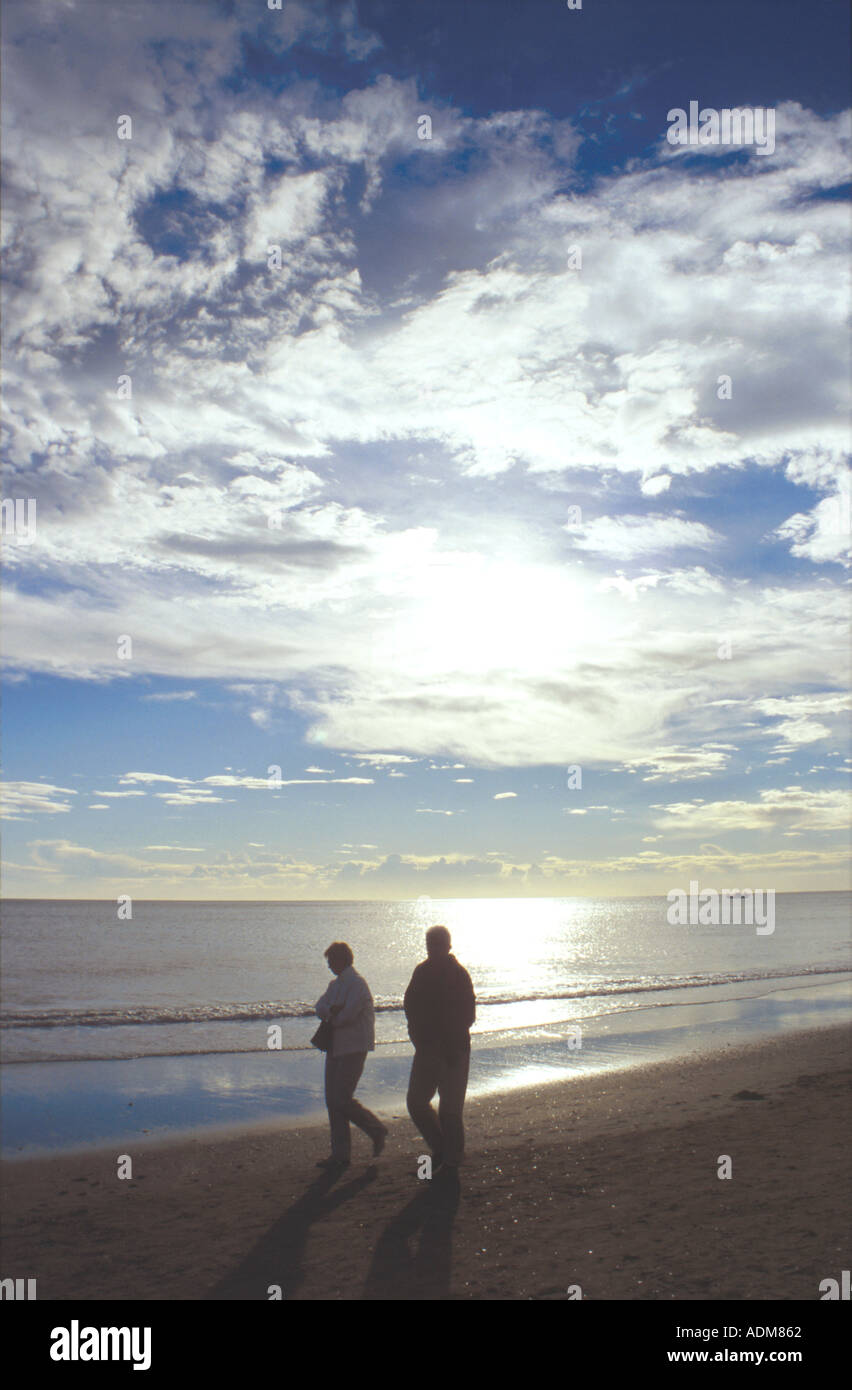 Couple walking hand in hand along beach at sunset hi-res stock ...