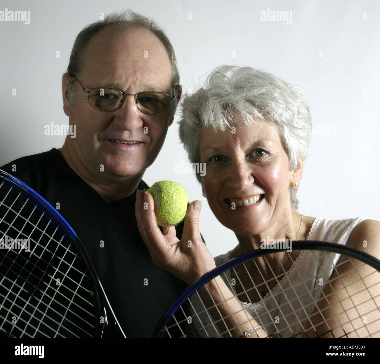 Active couple in their sixties with tennis rackets and ball Stock Photo ...
