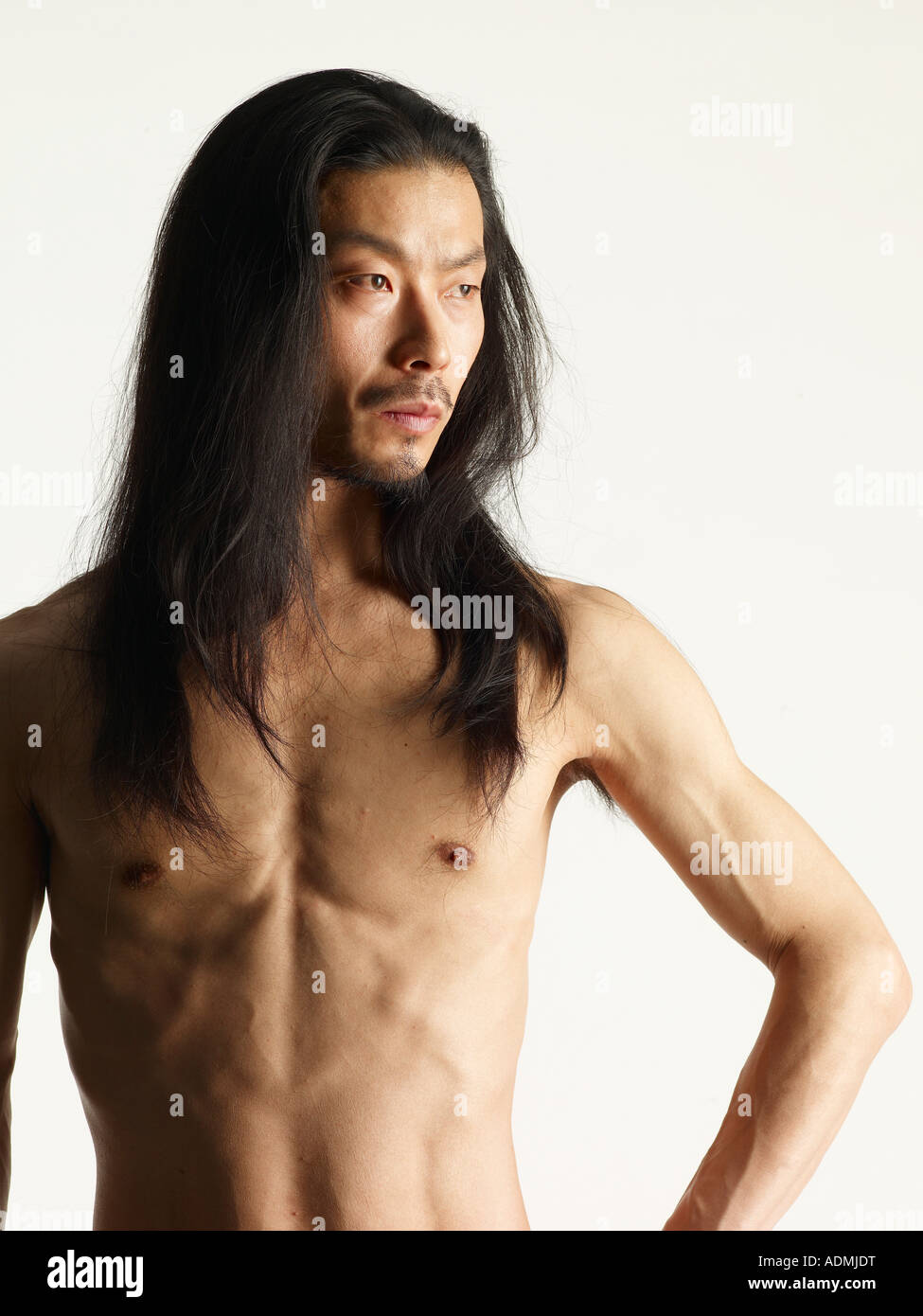 Shirtless young man with long hair hand on hip Stock Photo - Alamy