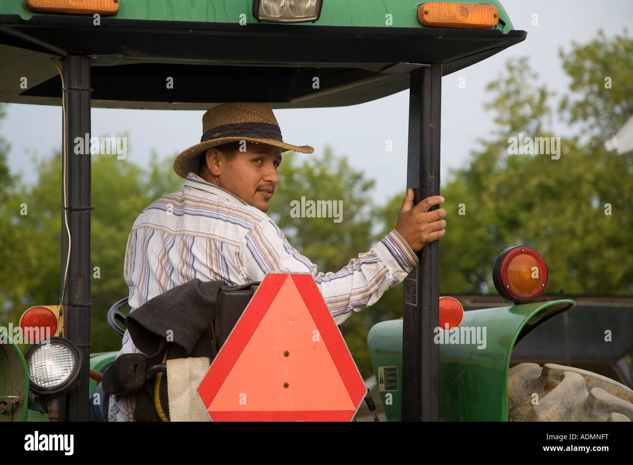 Mexican Immigrant Drives Tractor on Organic Farm Stock Photo