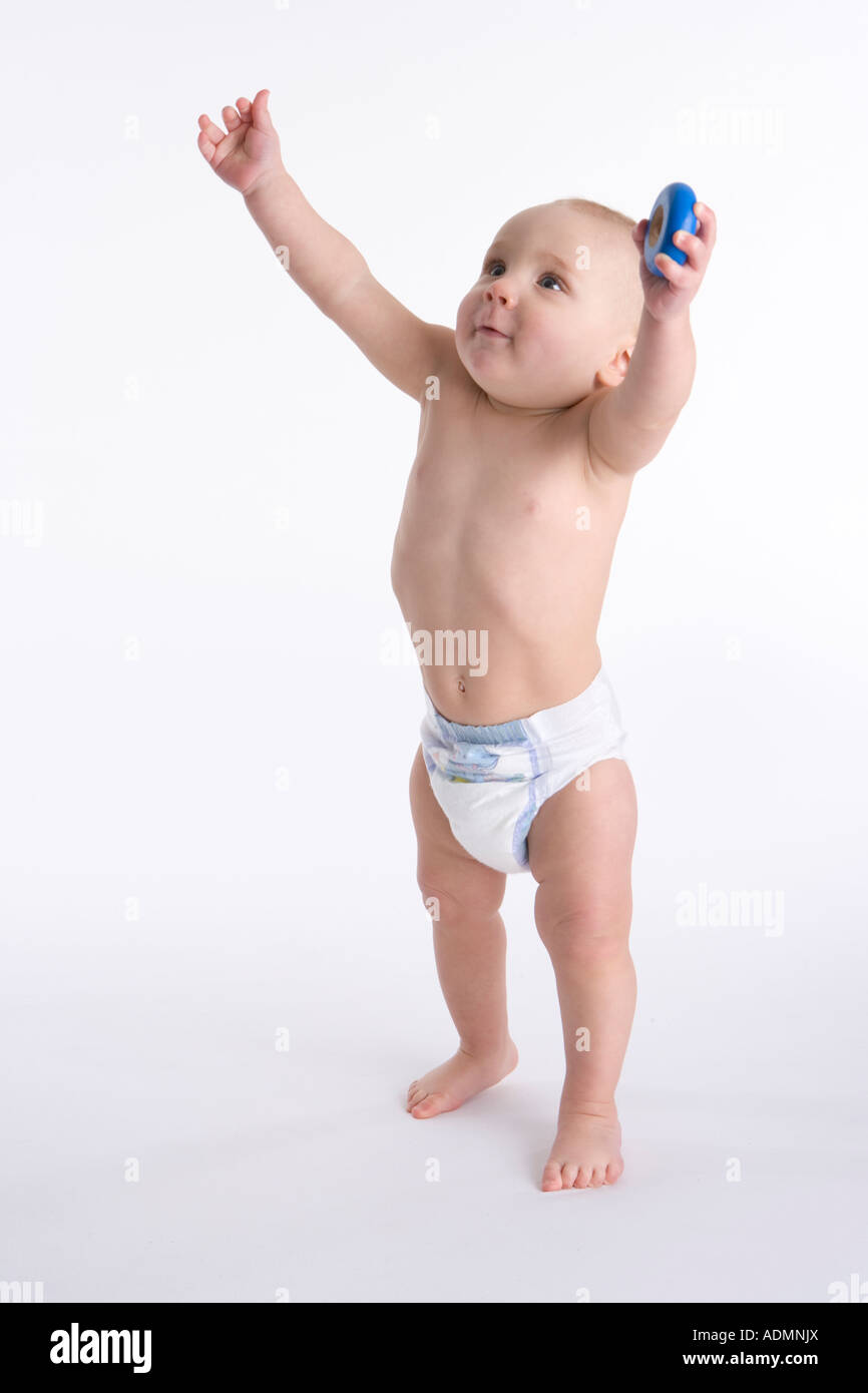 Little boy standing with his arms high reaching for his parent Stock Photo