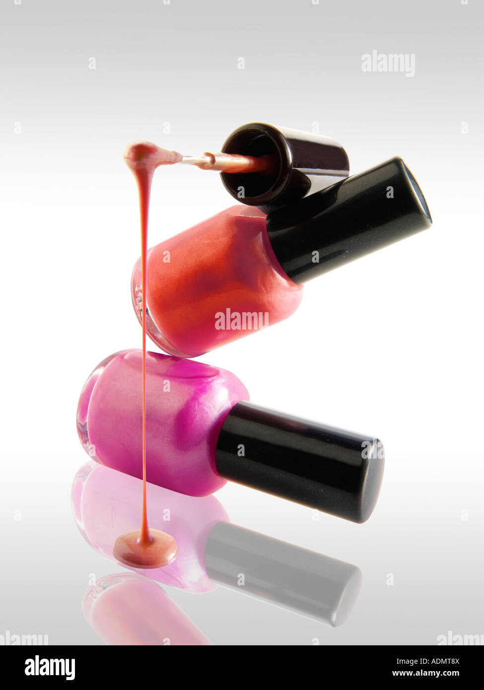 2 Nail Polish bottles balanced on each other in a fun way with a nail