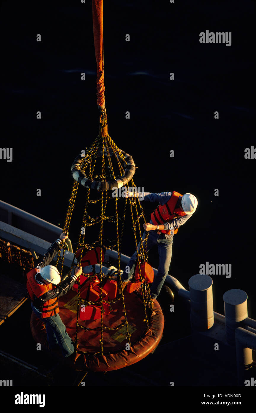 Two men are lowered onto an offshore oil rig from a crewboat based out