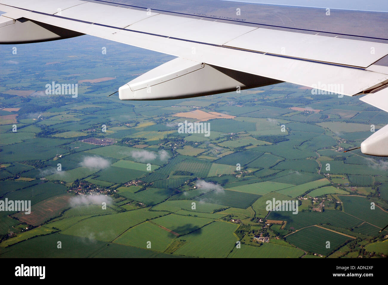Wingshot. View from passenger window of an aircraft showing tiny clouds in formation and land below Stock Photo