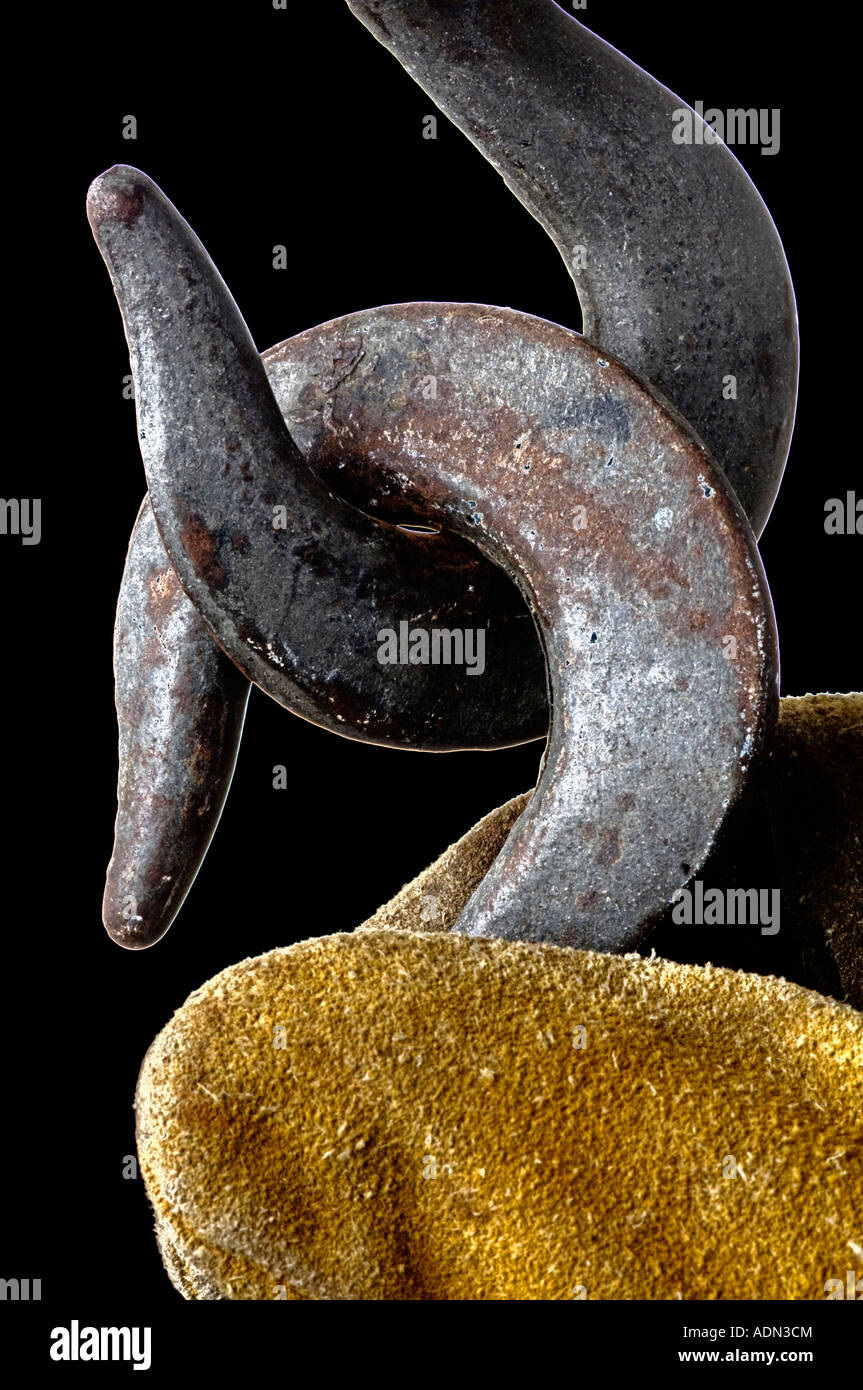 gloved hand of worker holding heavy duty steel hooks hanging from construction crane Stock Photo