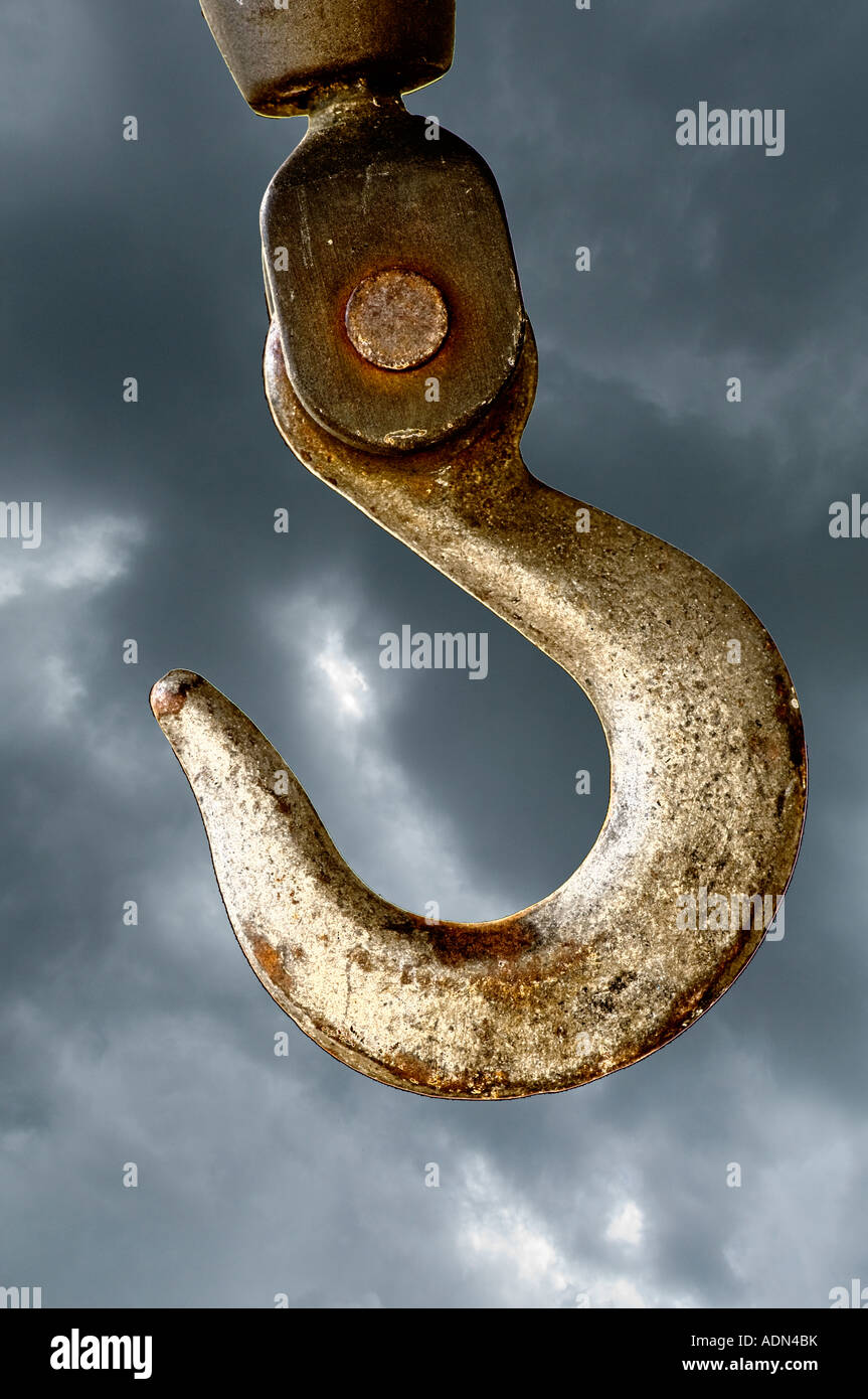 heavy duty steel hook hanging from large crane with stormy sky Stock Photo
