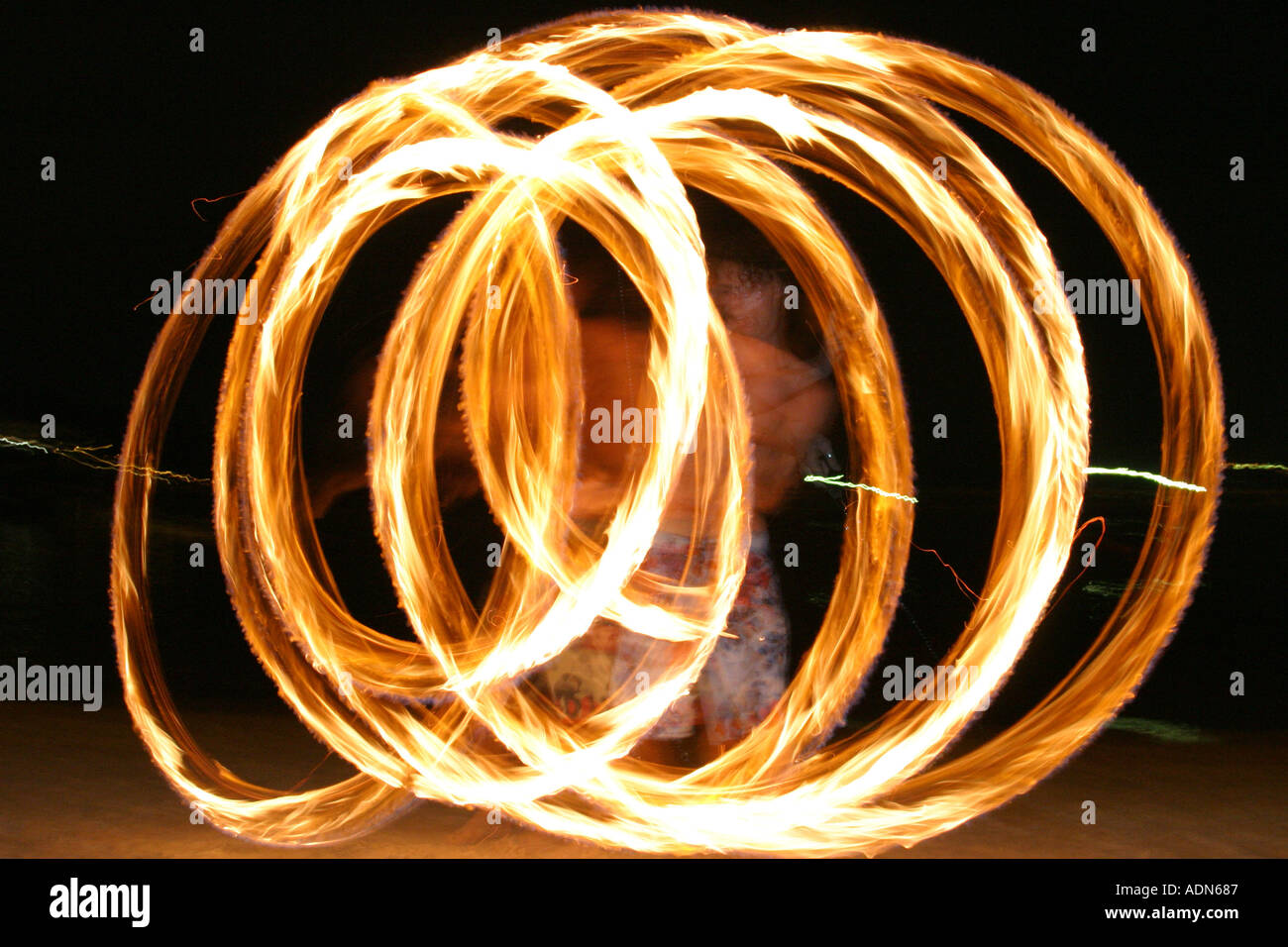 Young Man twirling fire on a beach at night Stock Photo