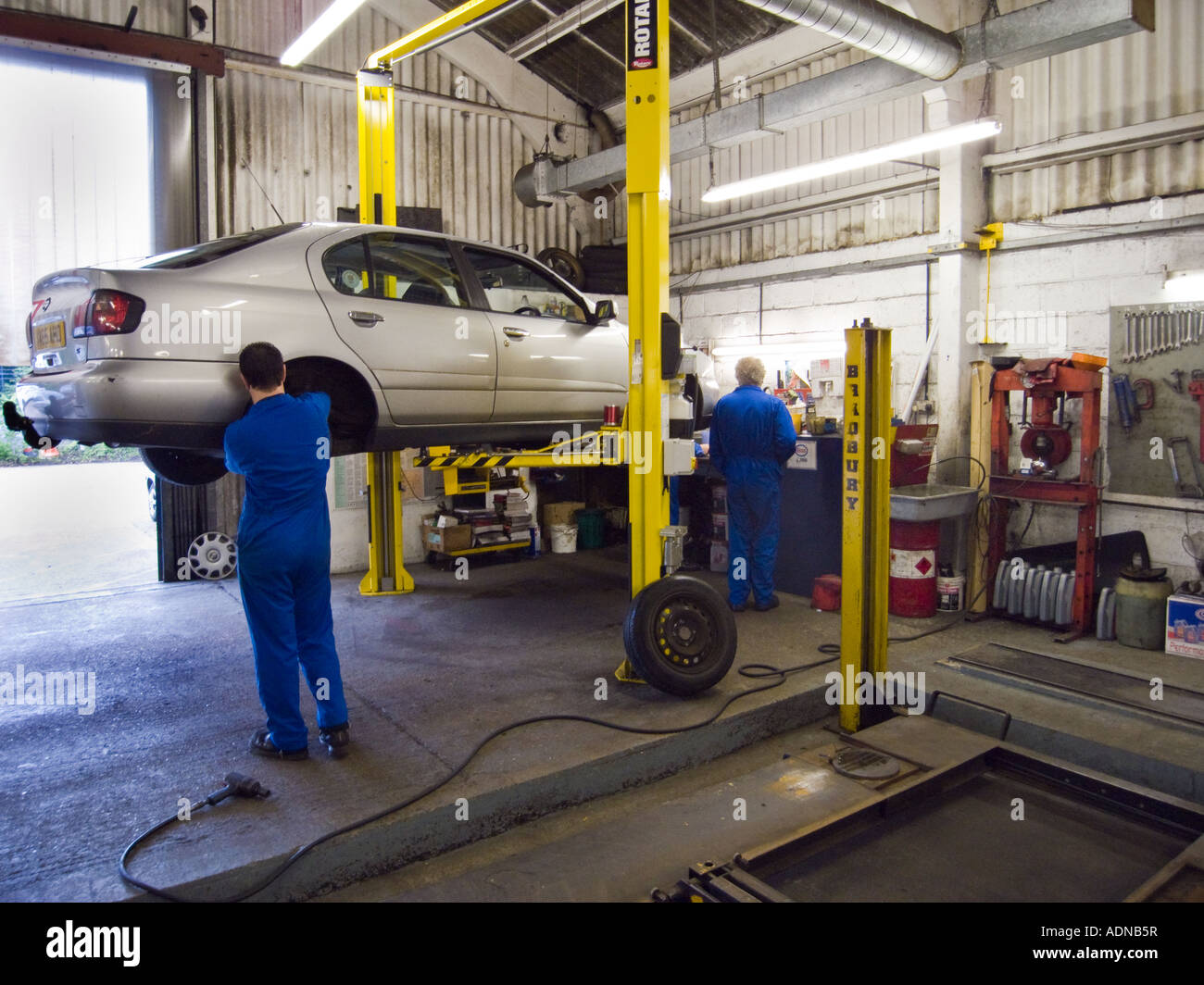 2 car mechanics working in a repair garage with hydraulic car lift ... - 2 Car Mechanics Working In A Repair Garage With HyDraulic Car Lift ADNB5R
