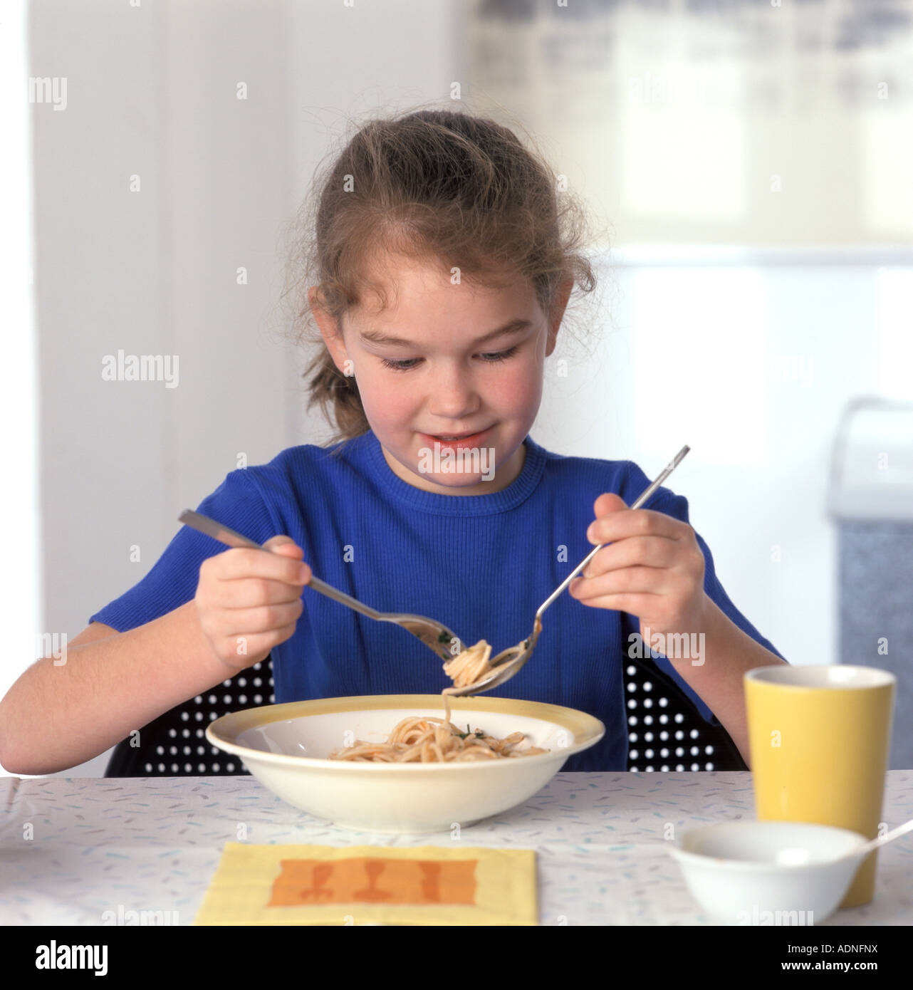 Girl eating pasta with a spoon and fork Stock Photo Alamy