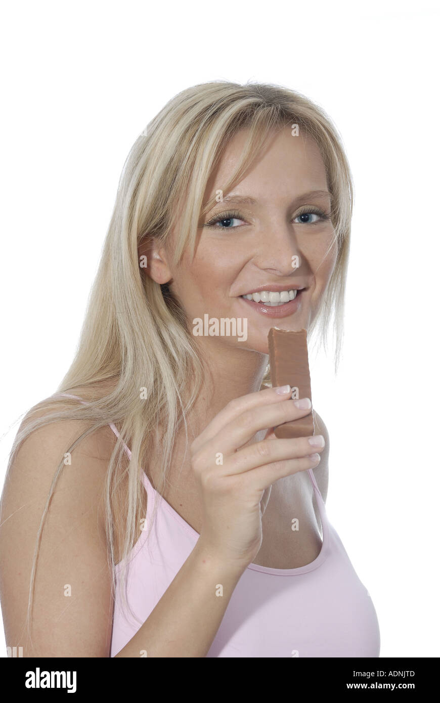 Junge Frau blond lacht laechelt freundlich positiv essen Genuss geniessen Schokoriegel Kalorien Stock Photo