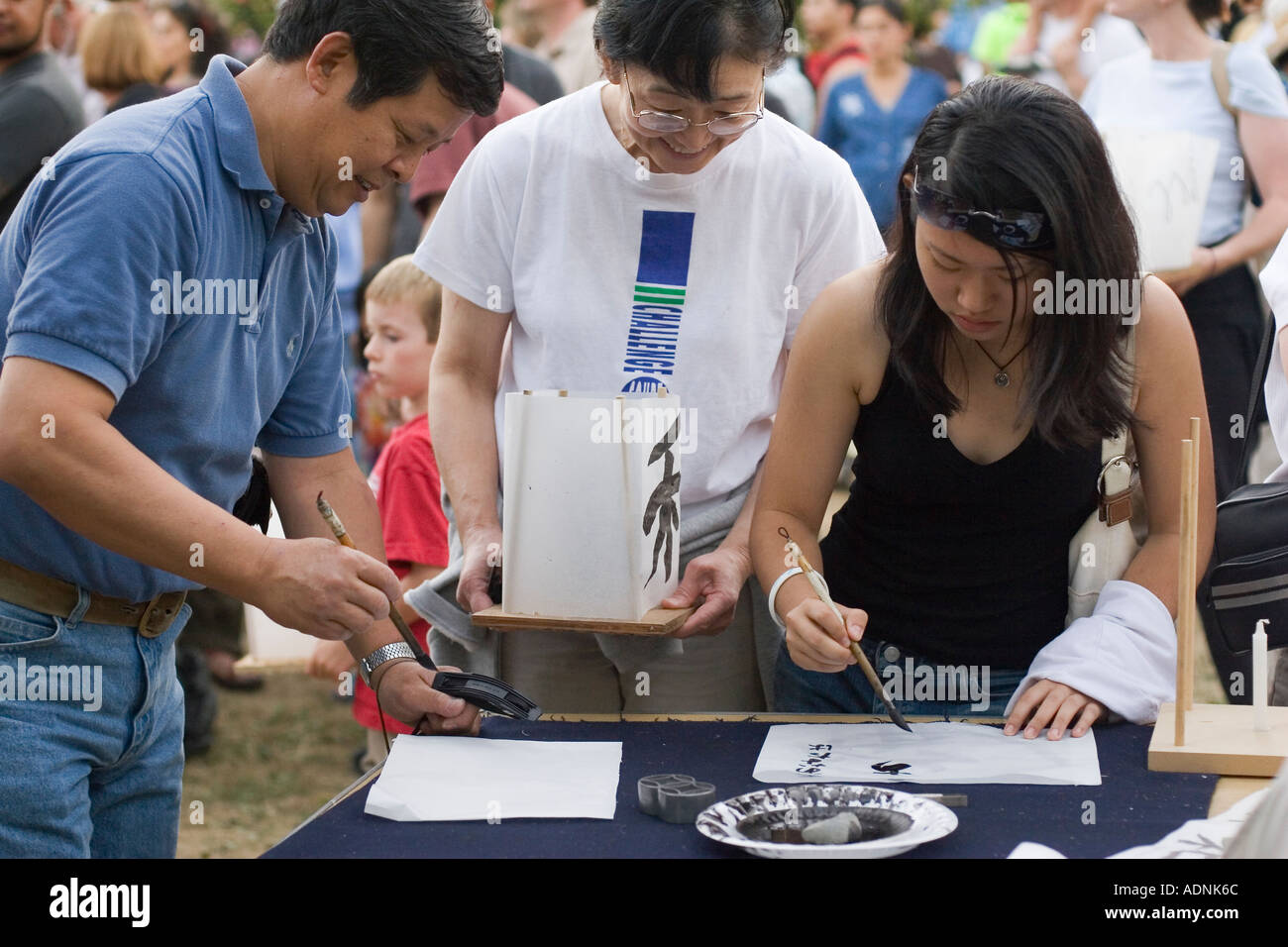 People painting Japanese script symbols on paper coverings of lanterns