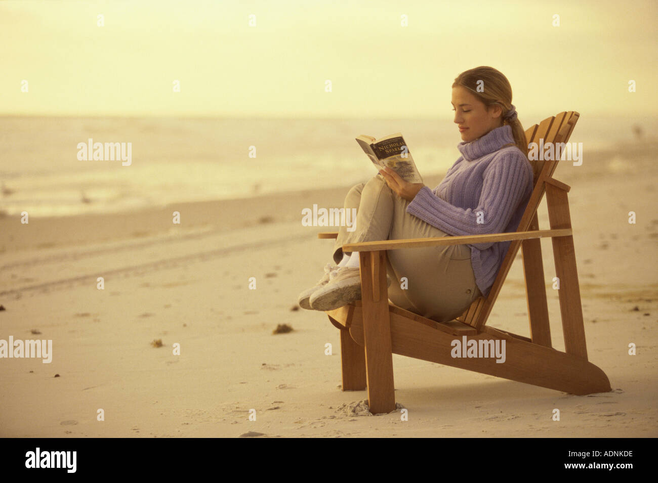 Side profile of a young woman reading a book on the beach Stock Photo ...
