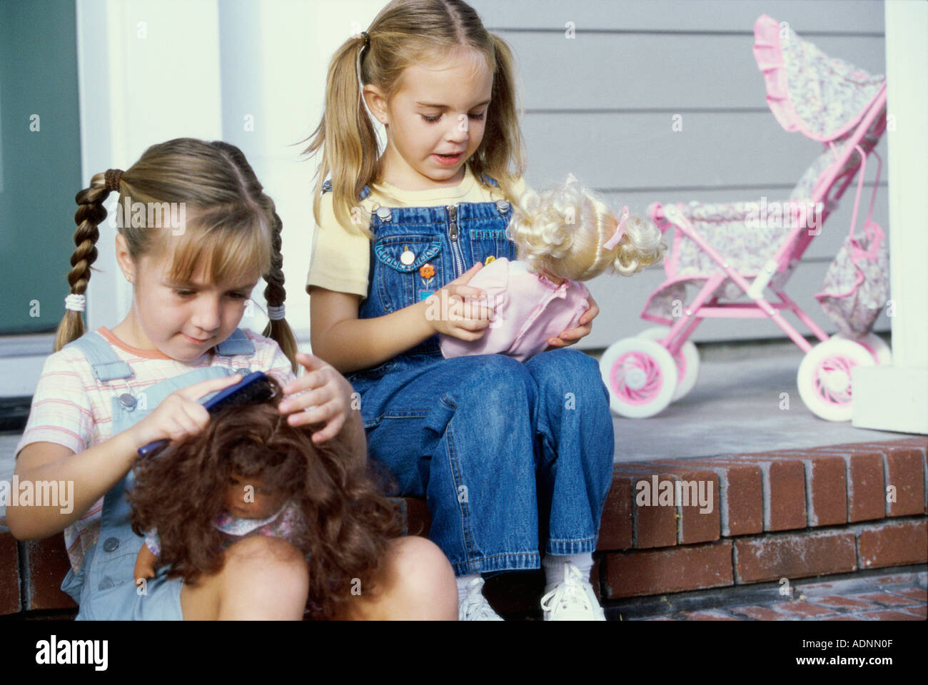 Two girls sitting together with their dolls Stock Photo