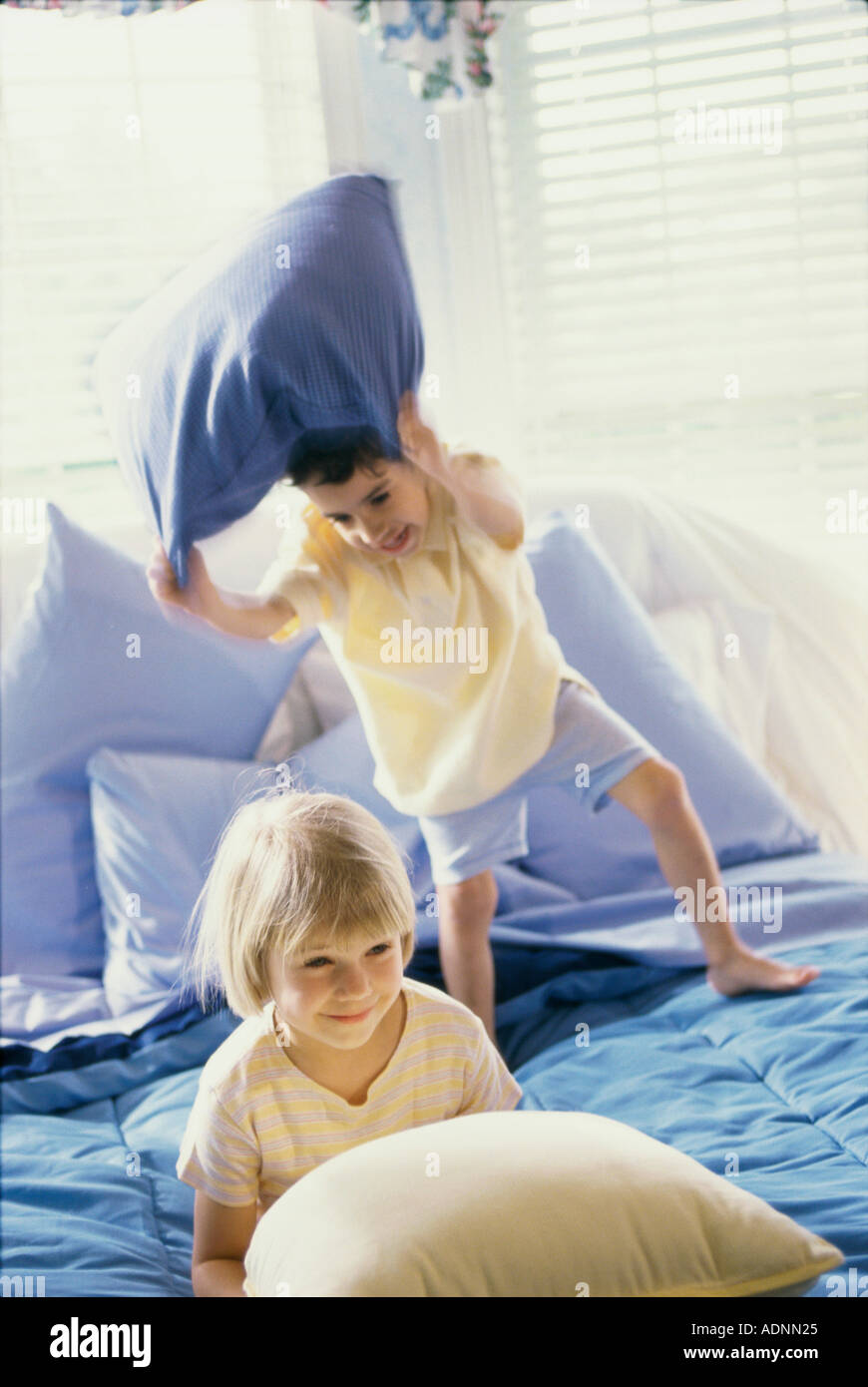 Boy And A Girl Having A Pillow Fight On A Bed Stock Photo 4395300