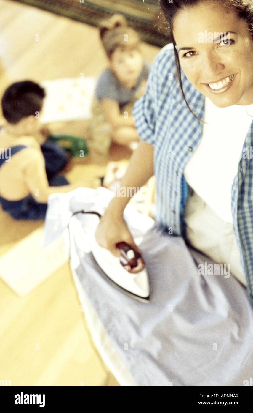 High angle view of a mother ironing clothes with her children playing