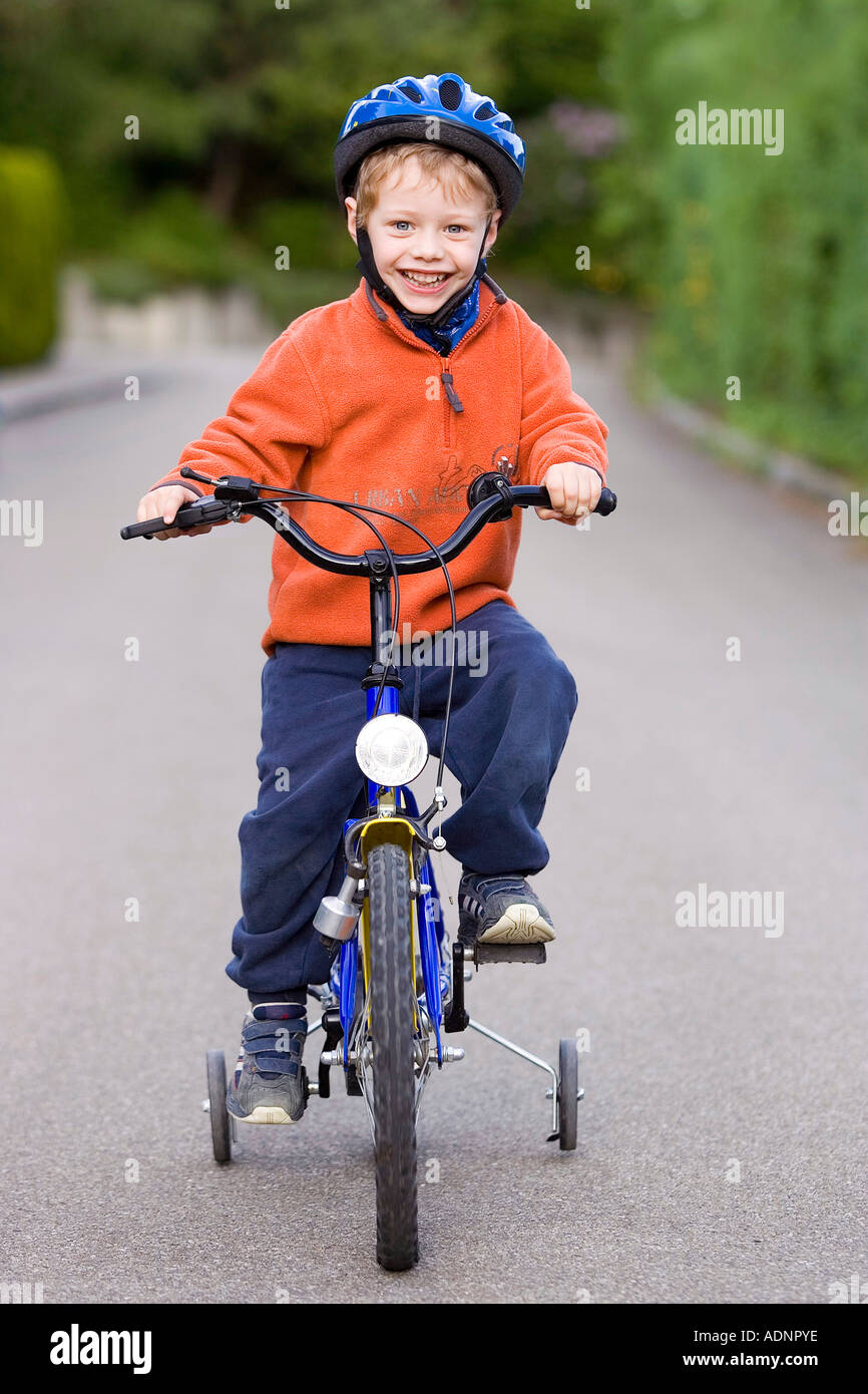 Little boy with hardhat on his bike with stabilisers Stock Photo