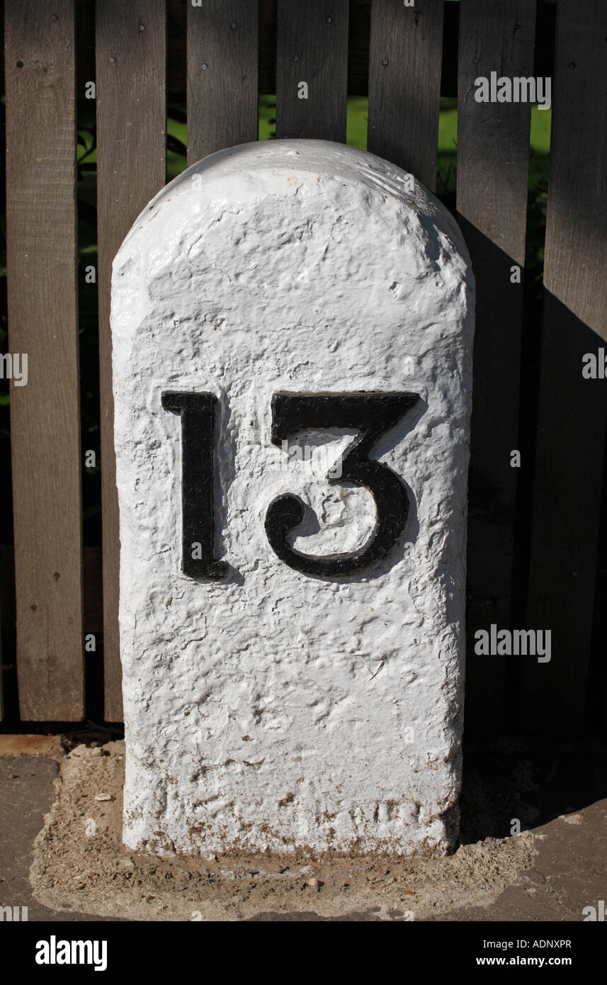 Milestone showing the number thirteen in black, unlucky for some. Sited in Heacham, thirteen miles to King's Lynn. Stock Photo