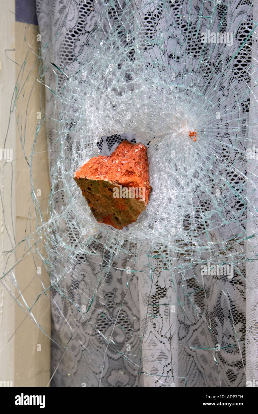 old red brick stuck in broken toughened strengthened glass window