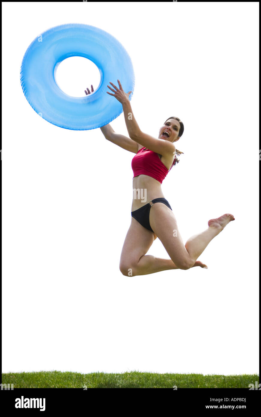 Woman in bikini jumping and smiling with swimming ring Stock Photo
