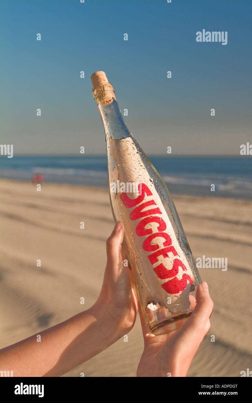 Hand holding message in a bottle against blue sky Stock Photo