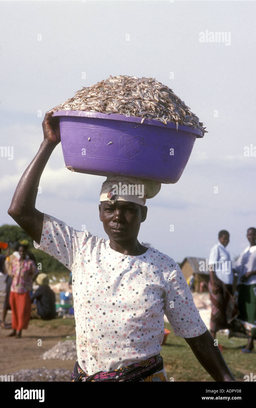 A Luo woman carrying a plastic bowl full of tiny fish called Cichlids on Rusinga Island Lake Victoria Kenya East Africa Stock Photo