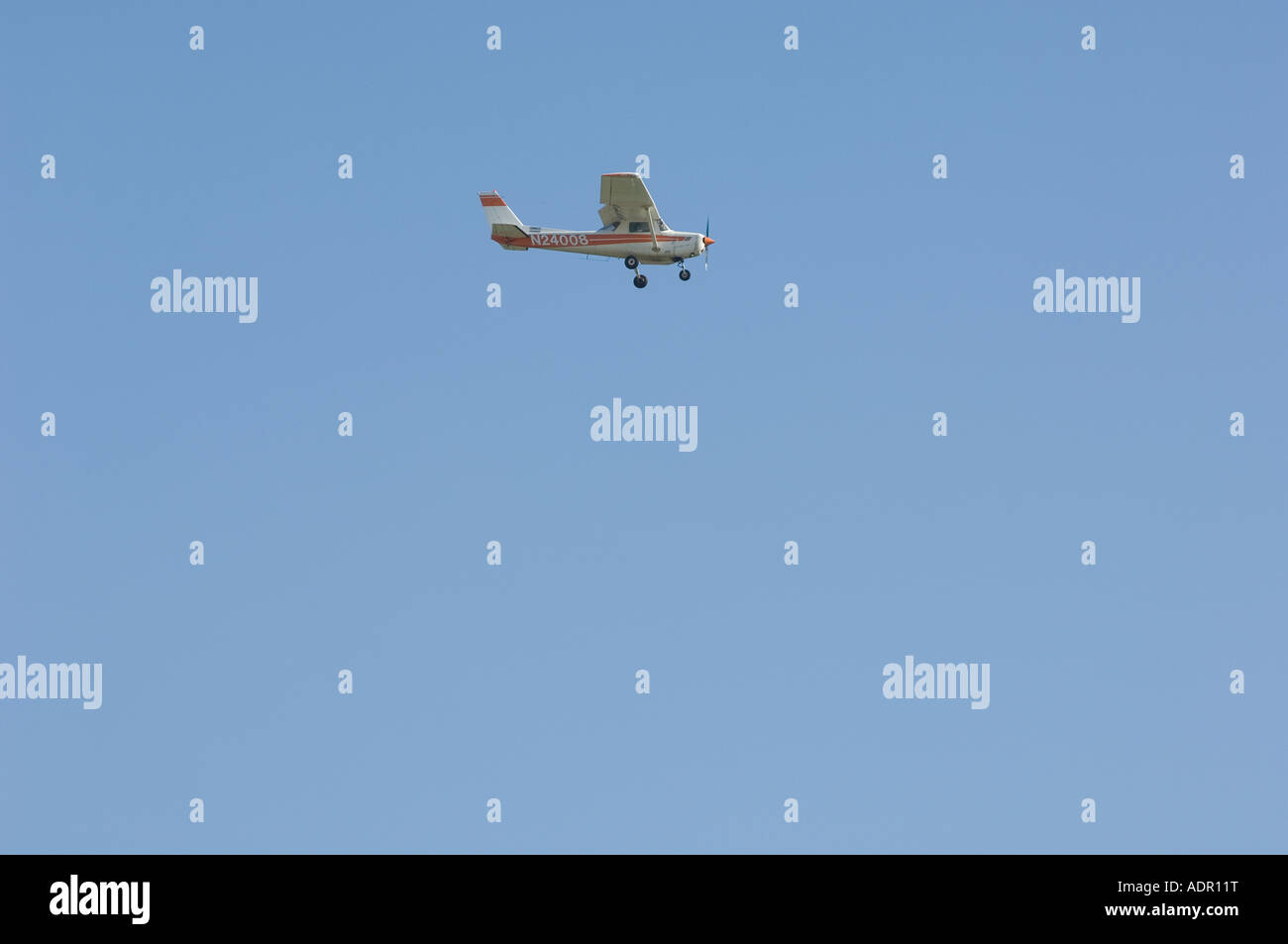 A Cessna 152 two seat single engine airplane flies along a blue sky Stock Photo