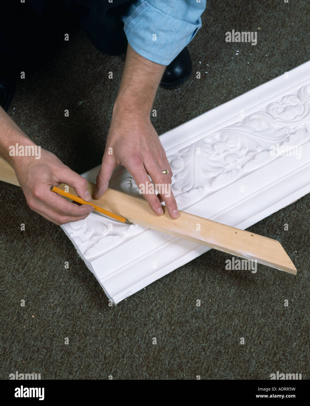 Man Measuring Plaster Cornice Before Cutting It To Fit Stock Photo