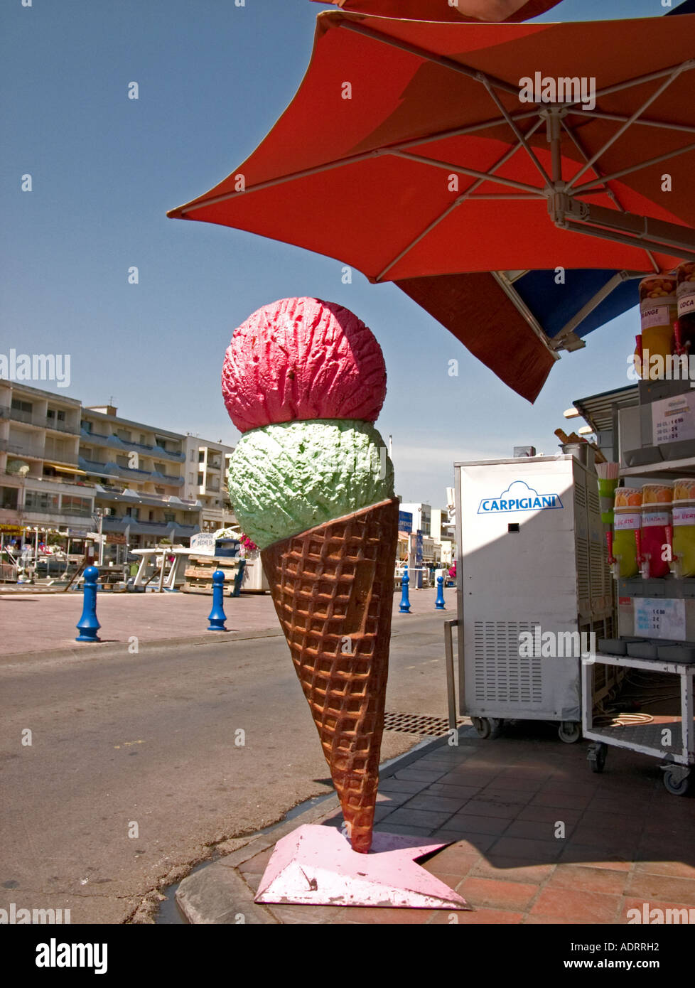 a large sculpture of an ice cream under a parasol on a pavement Stock Photo