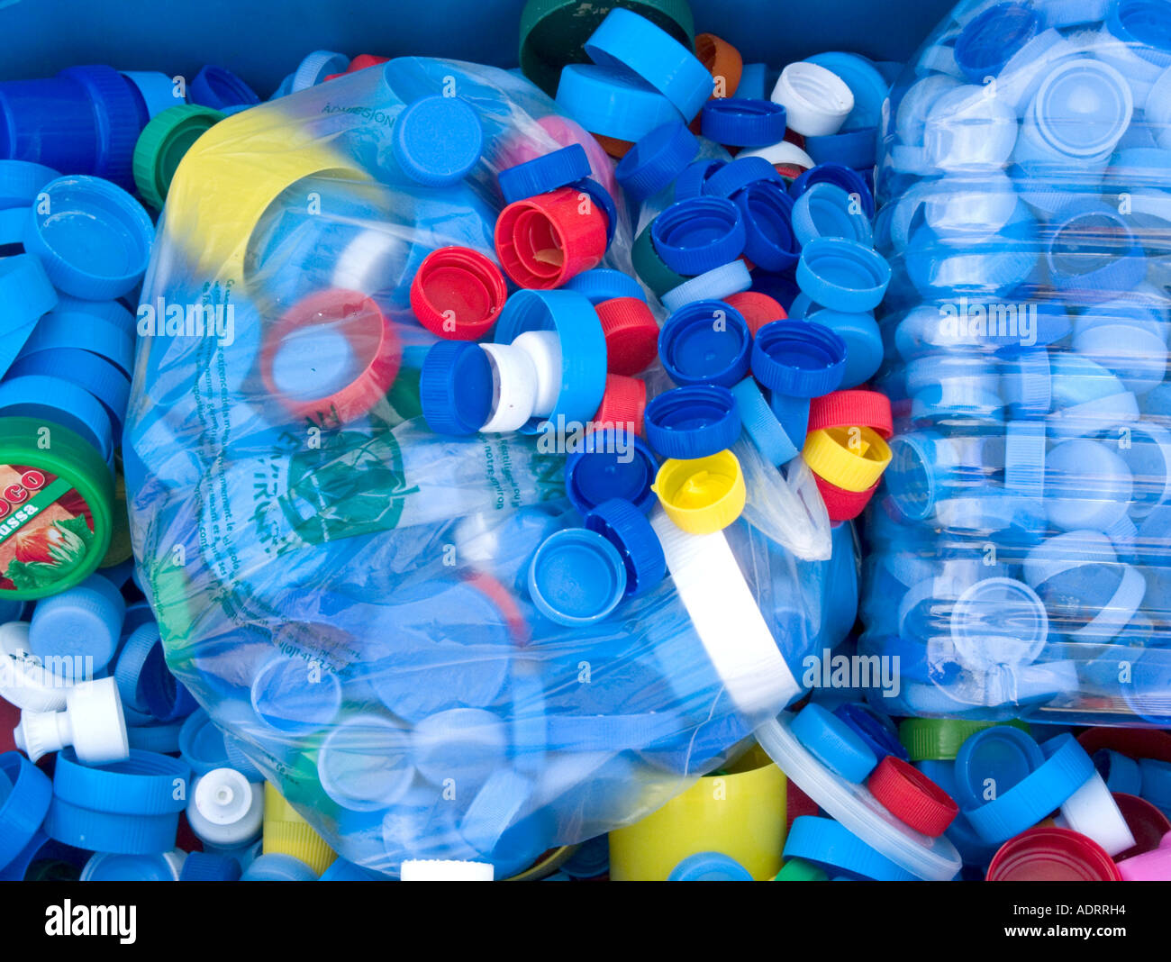 plastic bags full of multi coloured bottle tops lie amongst other tops Stock Photo