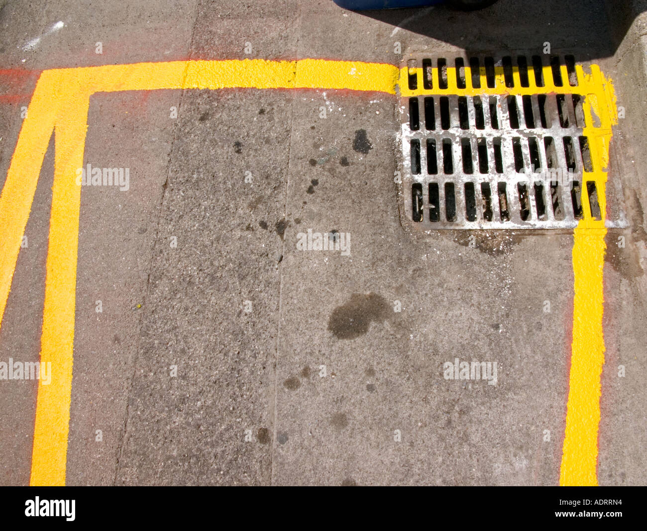 A detail of a freshly painted yellow road marking and a drain  from above Stock Photo