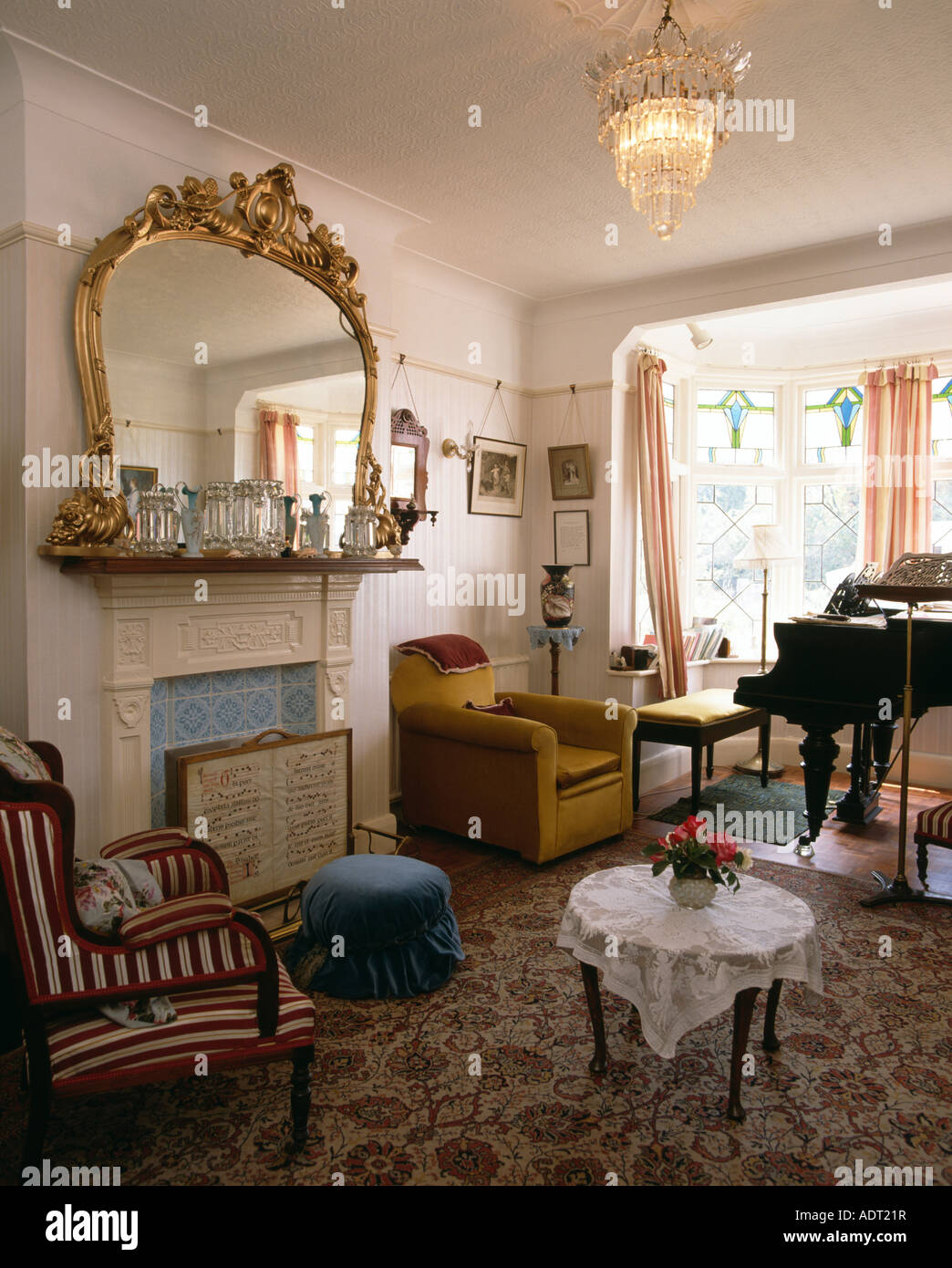 Ornate gilt mirror over fireplace in livingroom with piano and ...