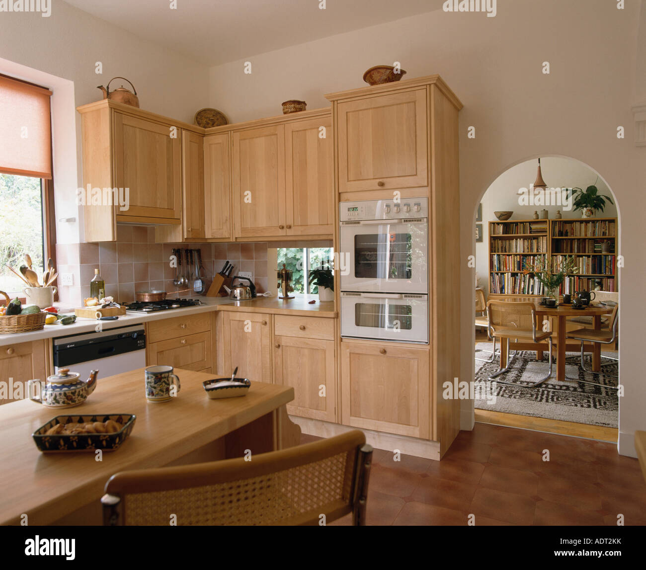 Pale wood units in eighties kitchen with arch in wall to diningroom ...