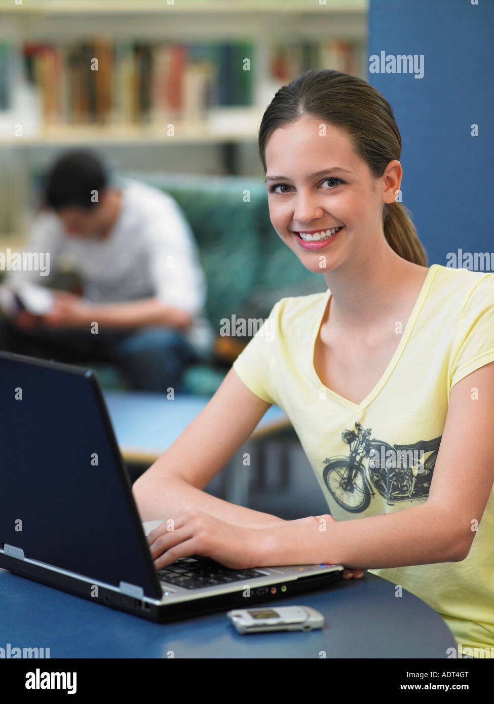 Teenage girl using laptop in library, portrait Stock Photo - Alamy