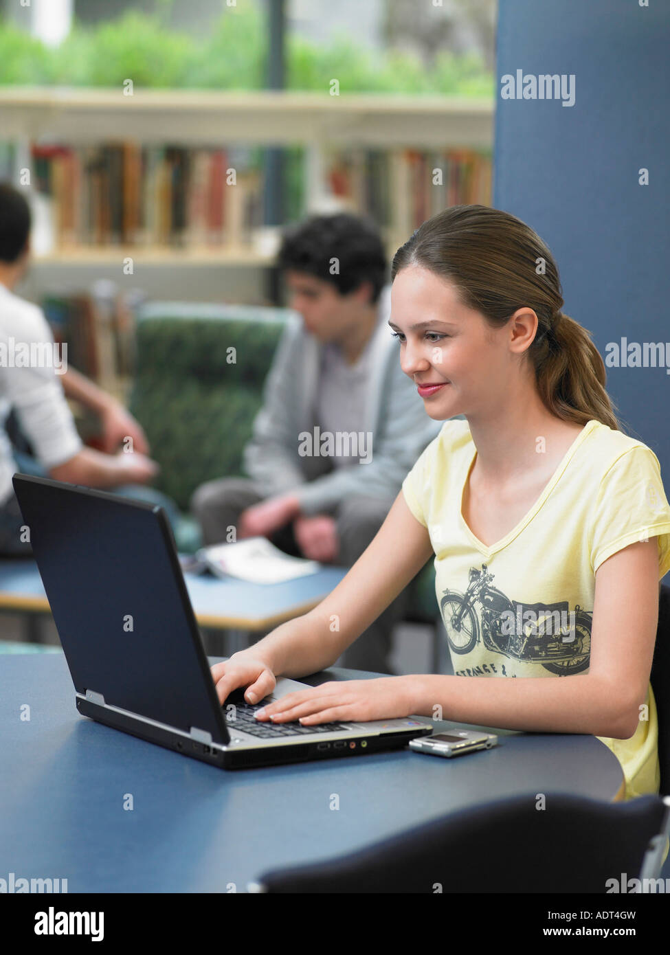 Teenage girl using laptop in library Stock Photo - Alamy