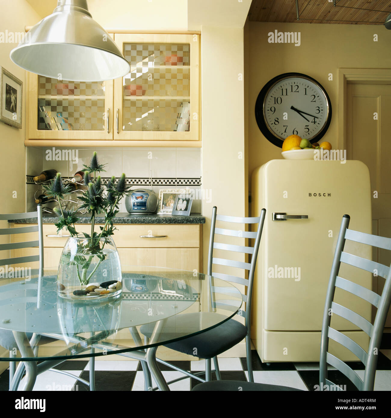 Circular glass table and metal chairs in modern neutral kitchen with