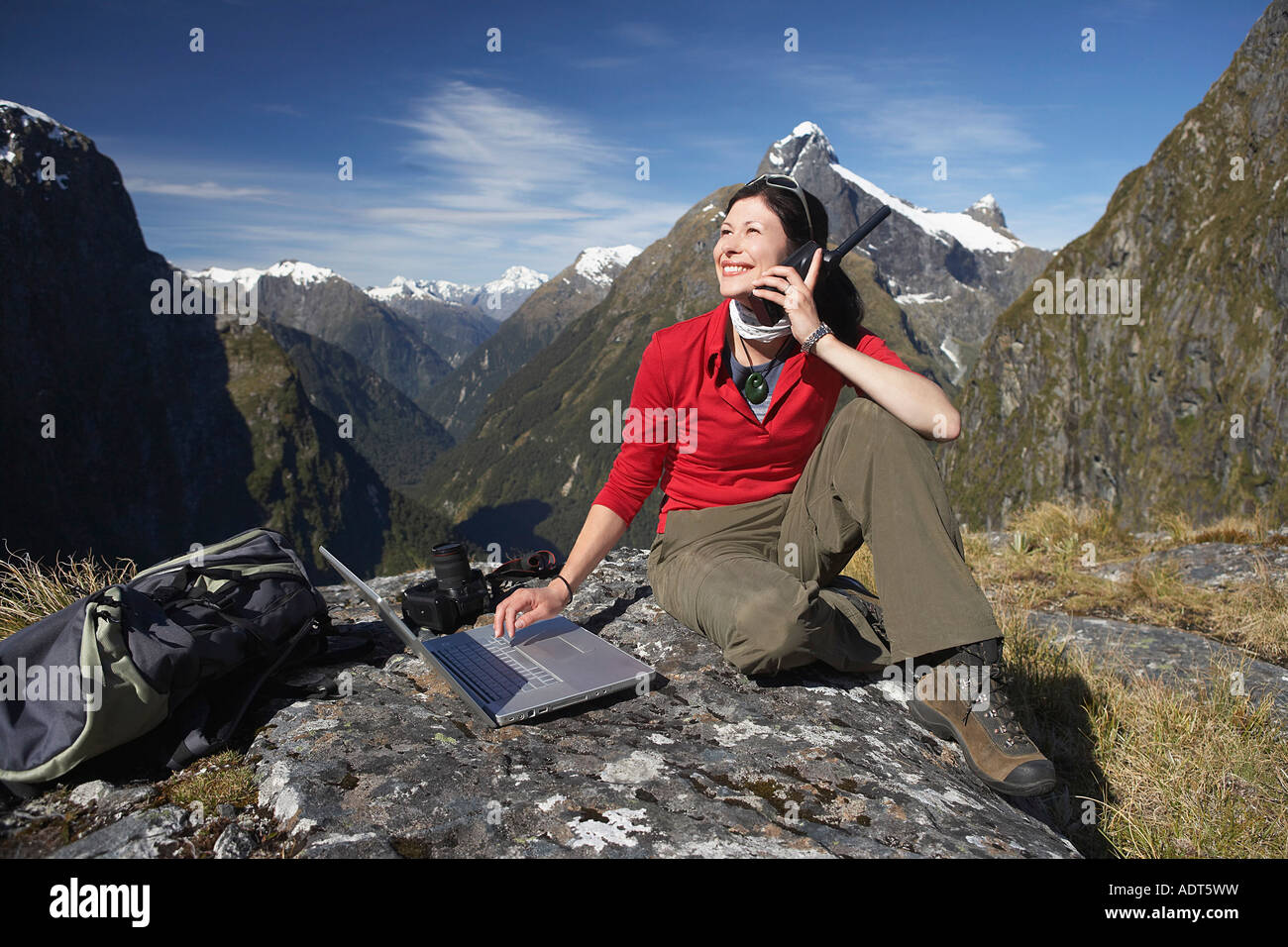 Woman using walkie-talkie and laptop on mountain peak Stock Photo - Alamy