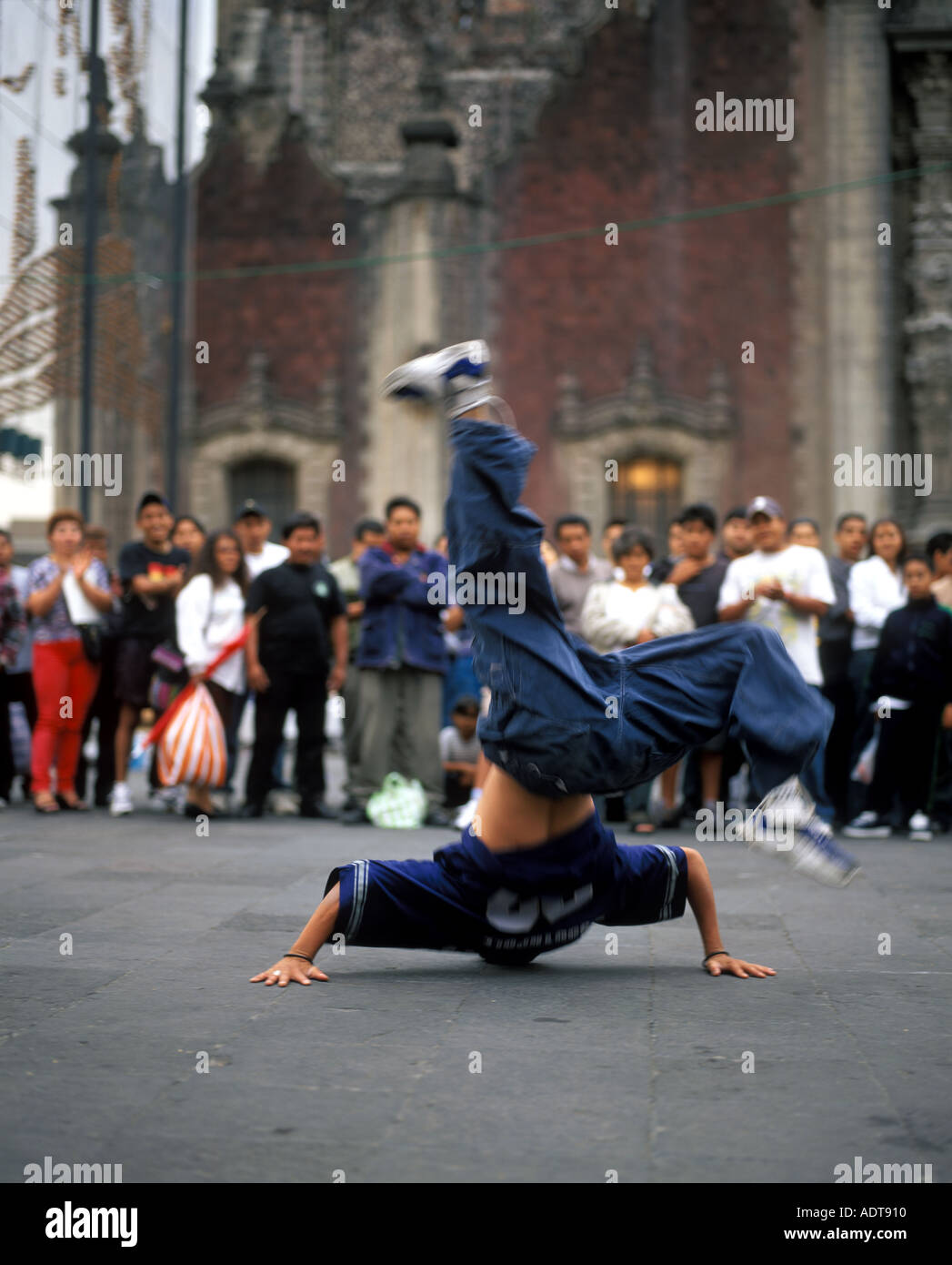A breakdancer does a handstand for a group of spectators in front of the Metropolitan Cathedral in Mexico City s Zocalo plaza  Stock Photo