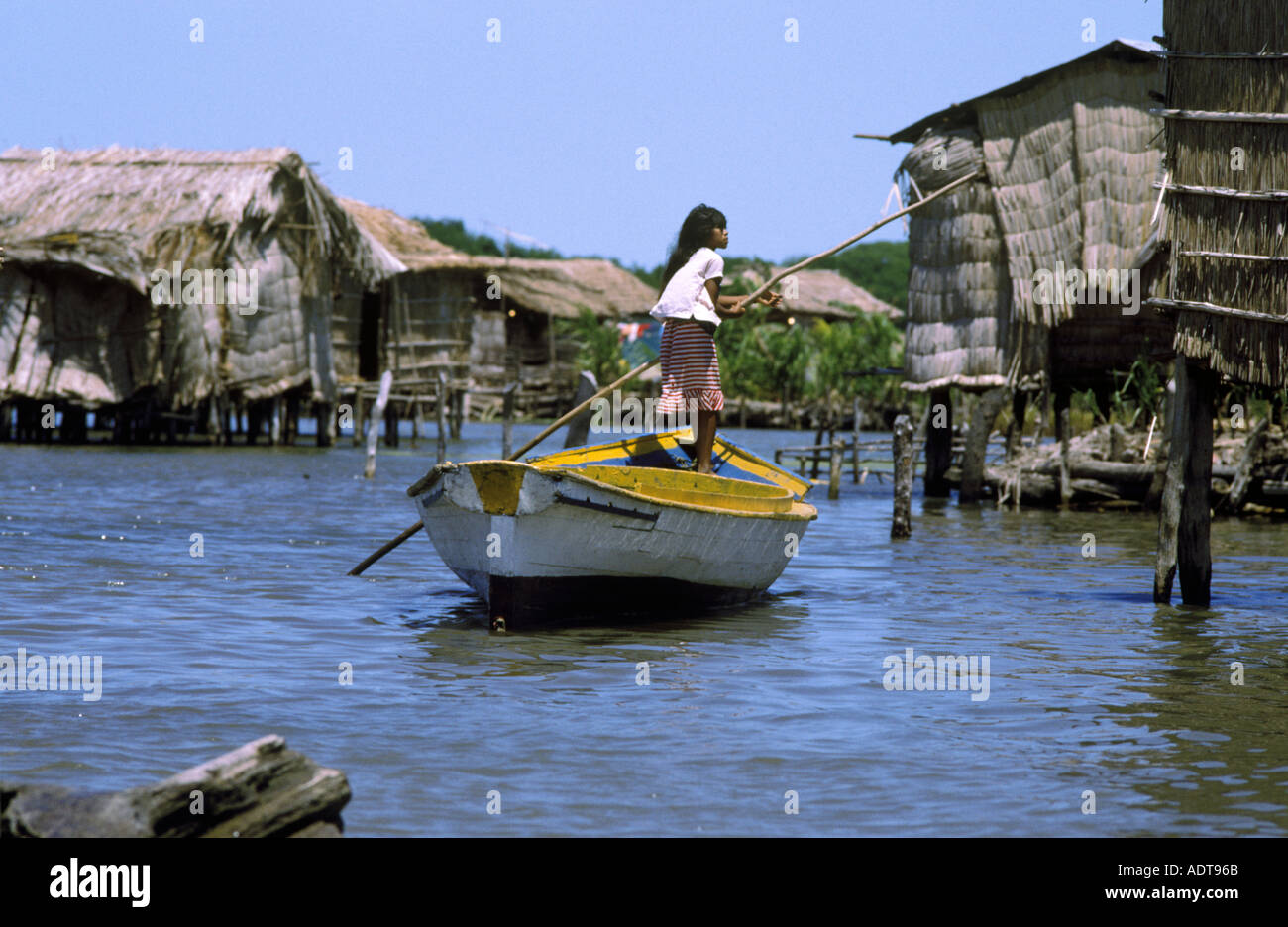 A young girl poles a boat to move between houses on stilts in Lake Maracaibo Venezuela  Stock Photo