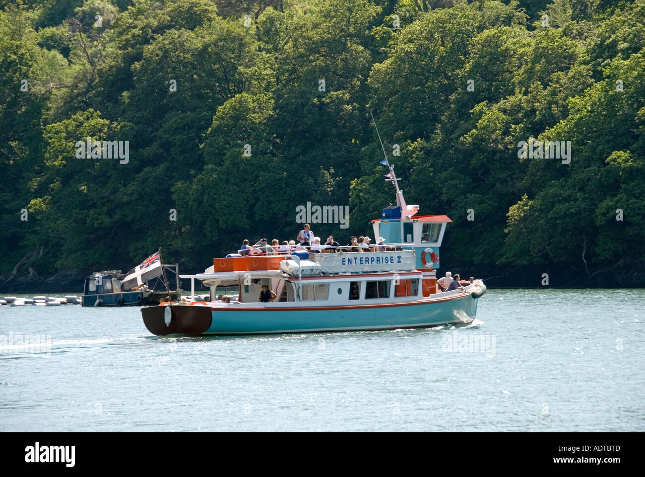 Trelissick river tour boat with passengers on Carrick Roads with woodland beyond Stock Photo