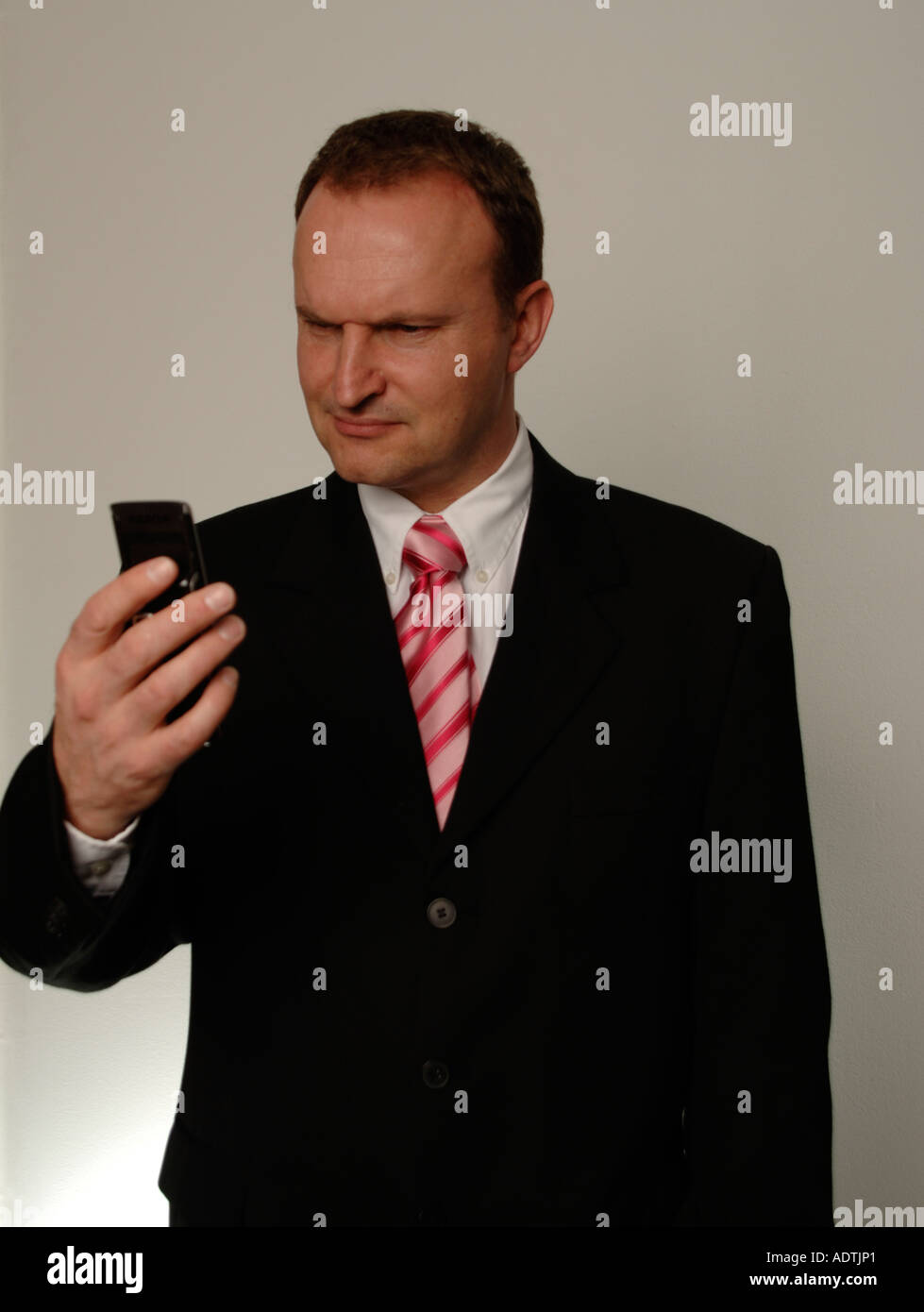Man in suit looking at mobile - perplexed Stock Photo