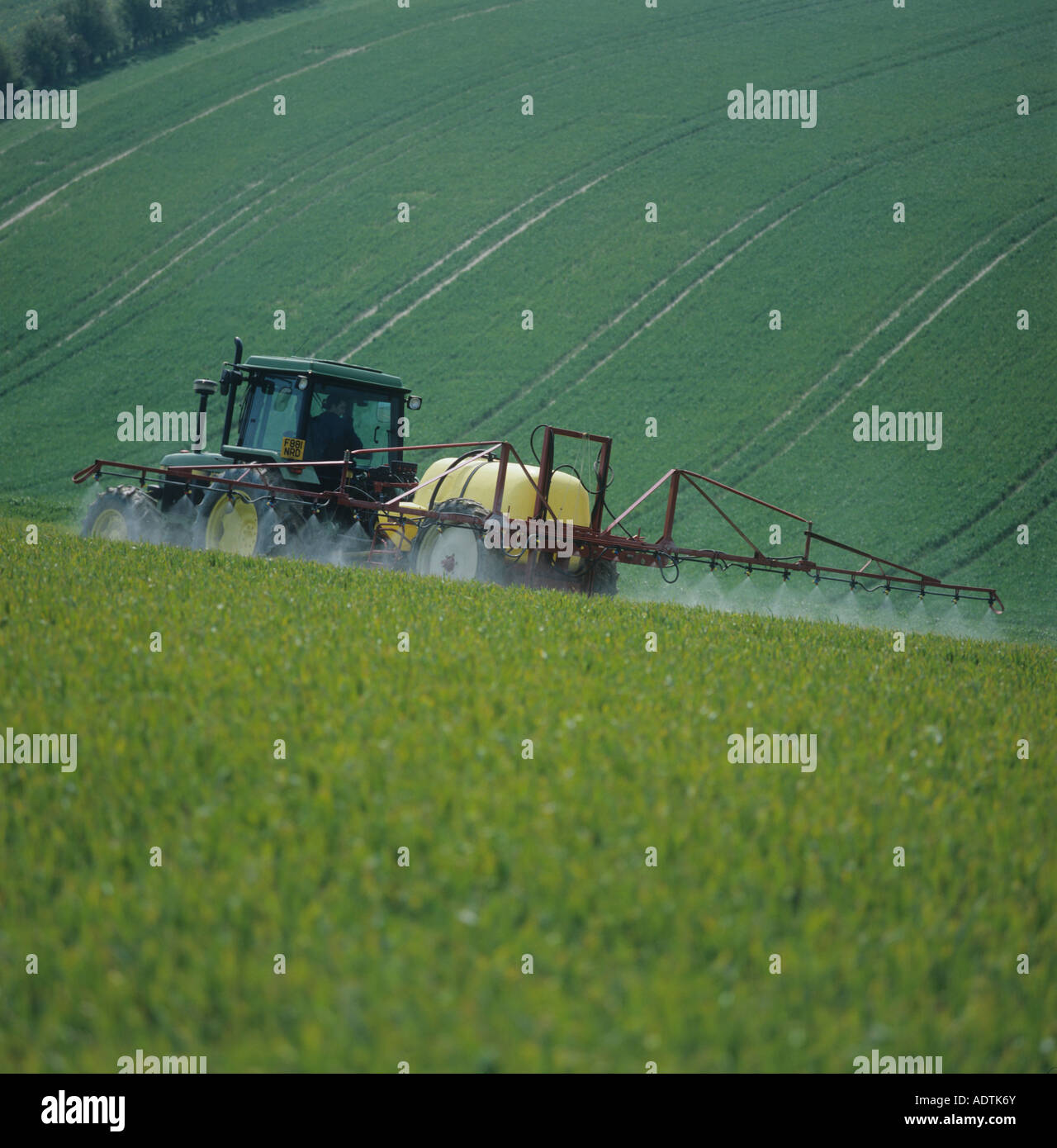 John Deere tractor and Hardi trailed sprayer spraying wheat crop at stage 30 in spring Stock Photo