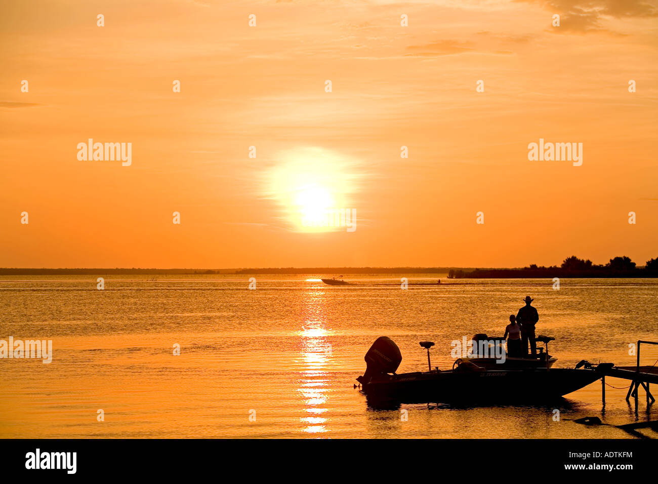 Fishing boat water ski sunset Texas Lake. Texas cowboy and wife standing in boat. Stock Photo