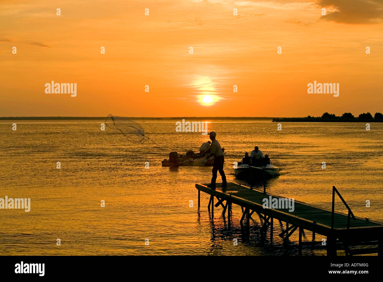 Fishing dock boats throw net sunset orange Texas lake Stock Photo