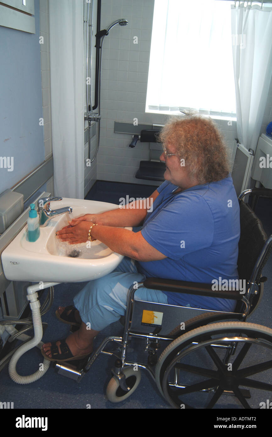 Disabled woman washes her hands in a specially adapted sink for