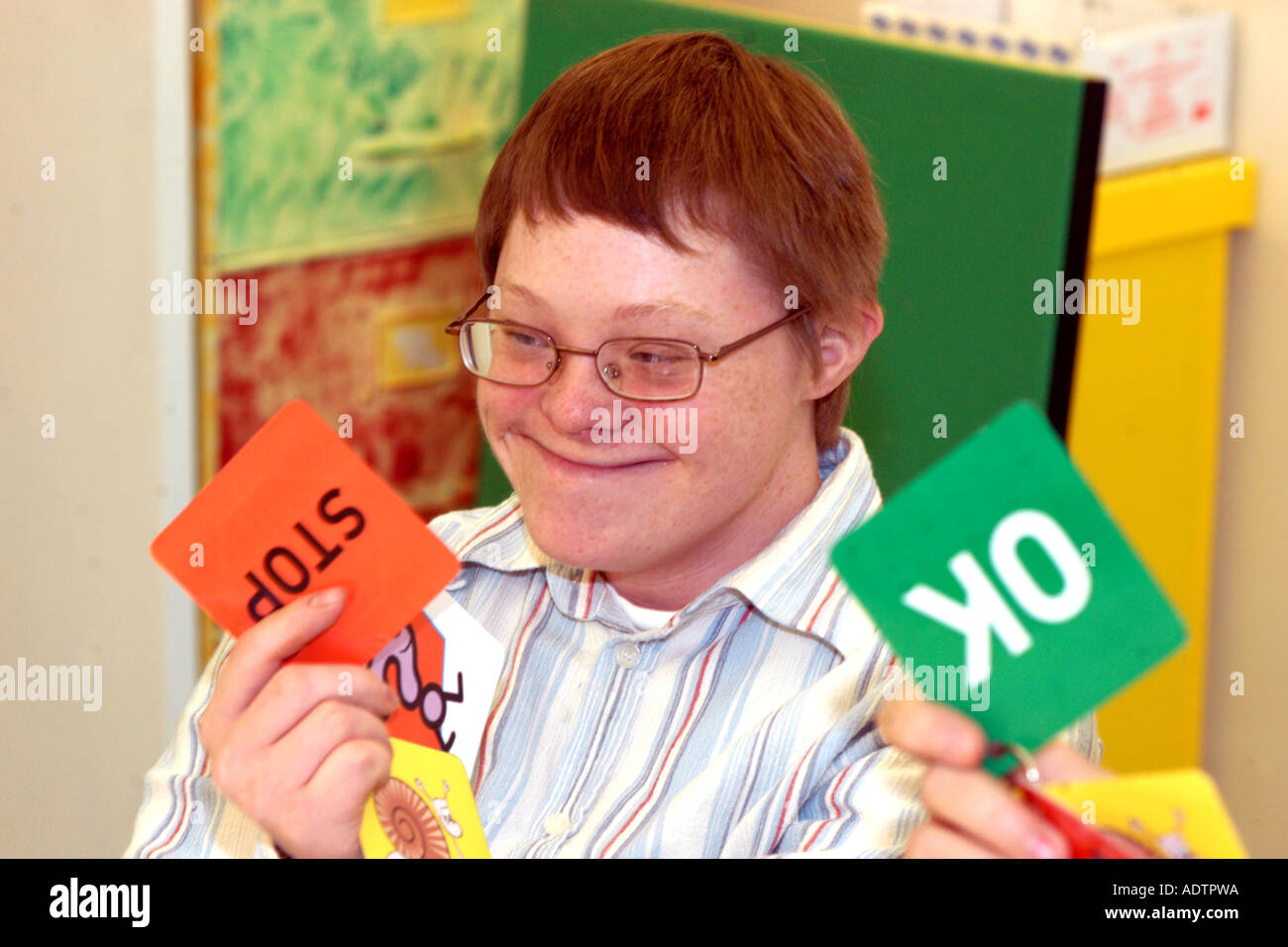 A young Downs Syndrome man at a Learning Disabilities support group meeting uses cards to express himself in meetings to aid com Stock Photo