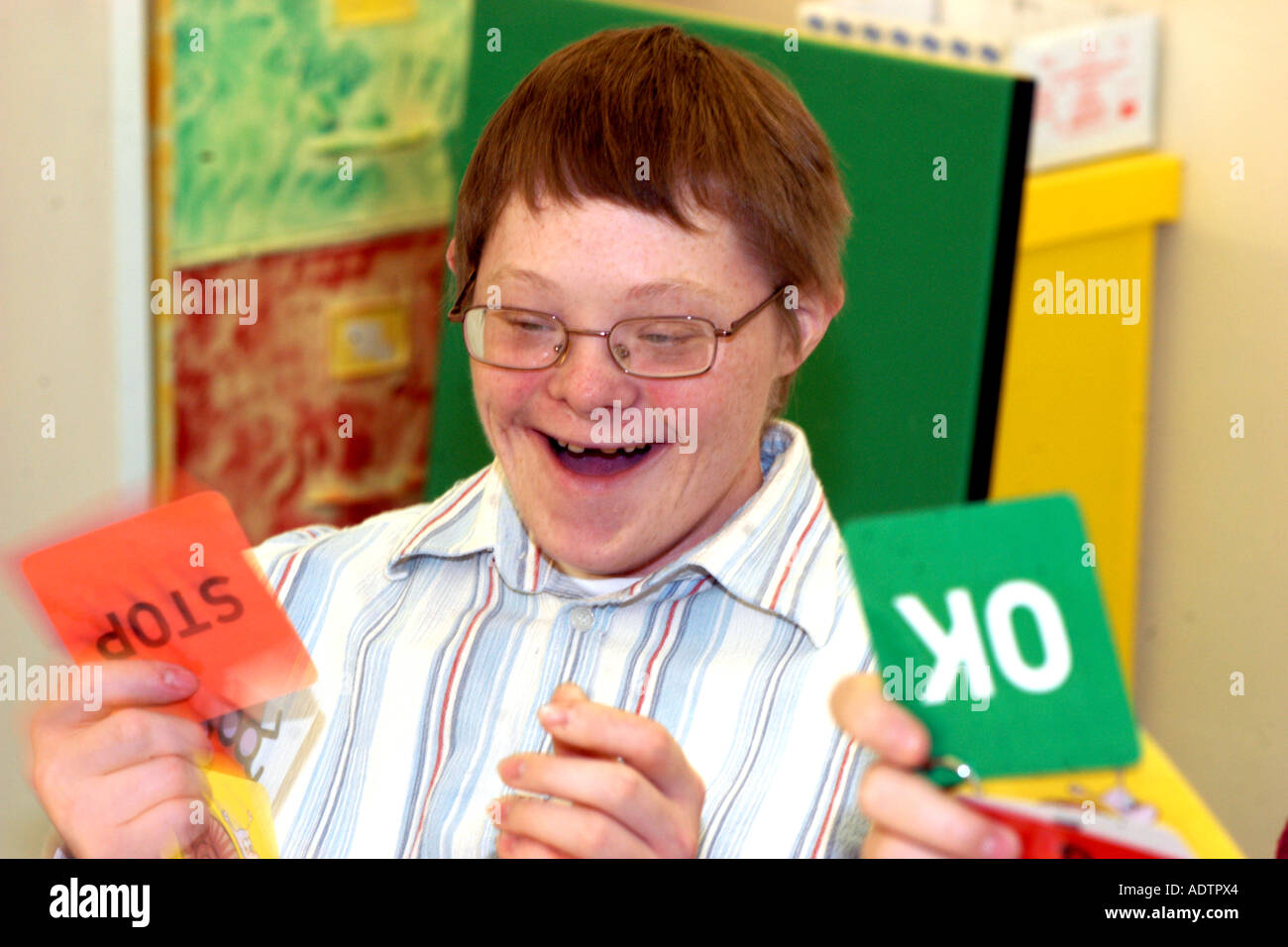 A young Downs Syndrome man at a Learning Disabilities support group meeting uses cards to express himself in meetings to aid com Stock Photo
