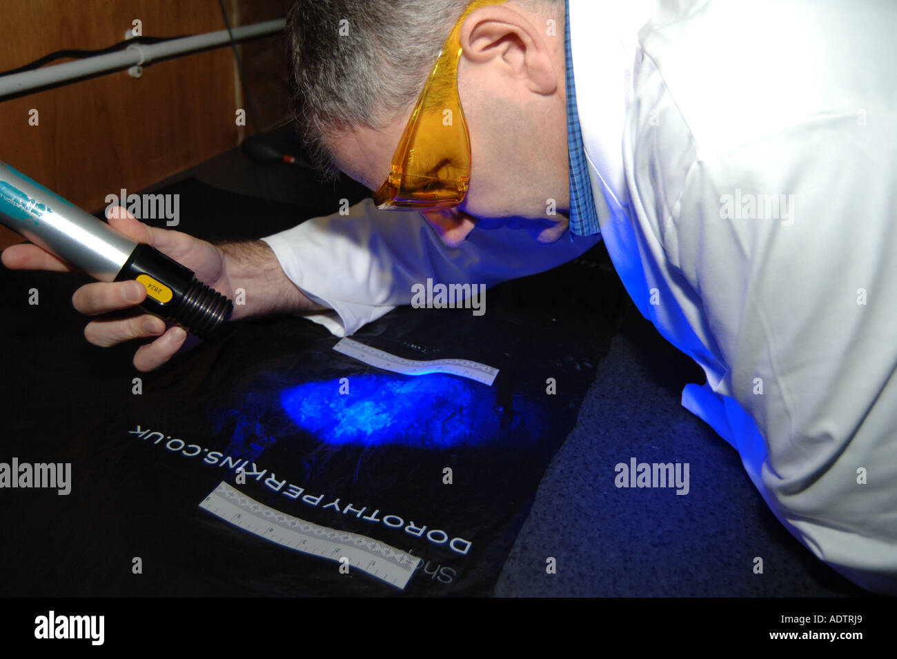 Forensic Police Officer searches for fingerprints on a plastic bag for evidence of crimes UK Stock Photo