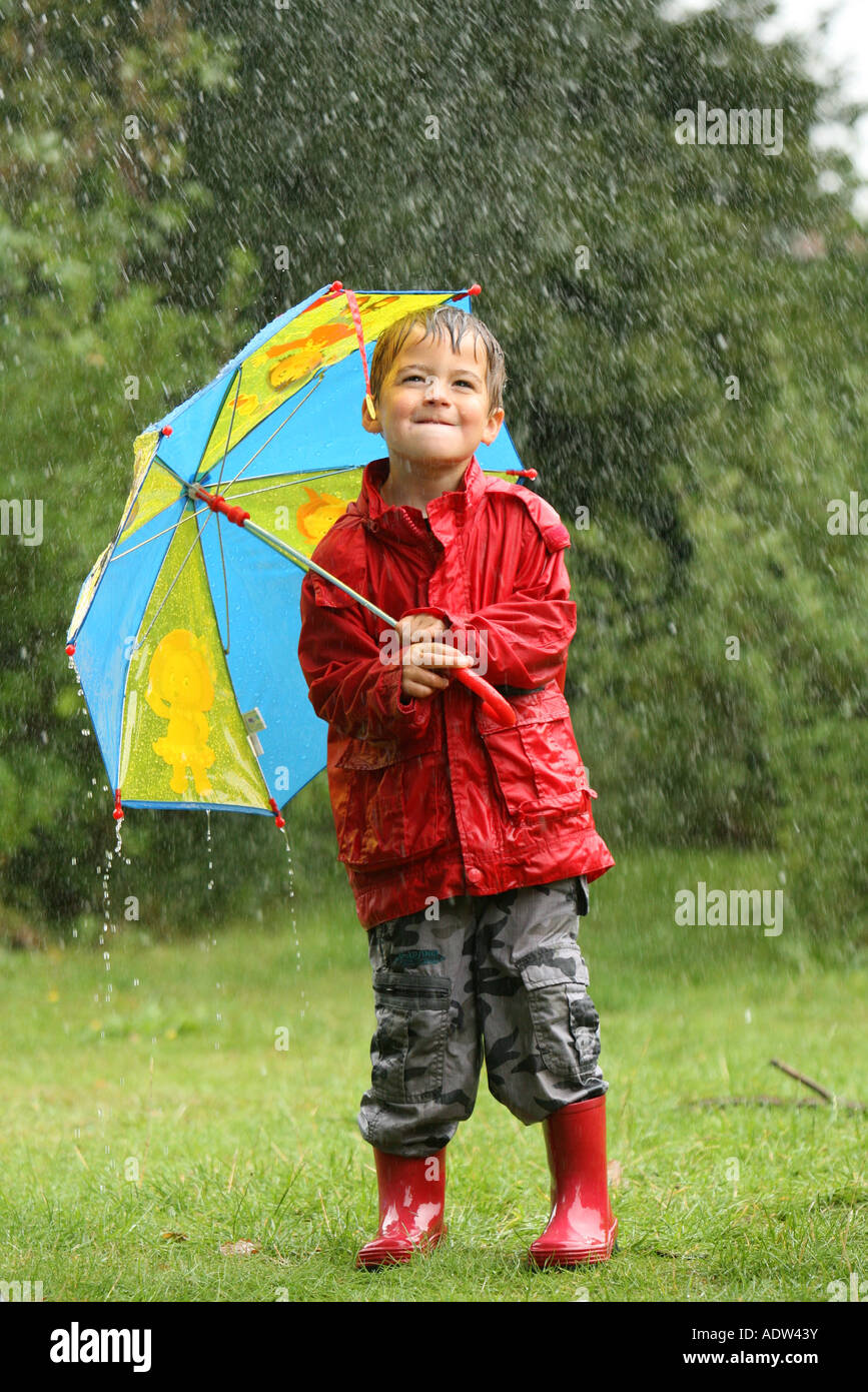 a young boy braves the wet weather rain storm with his umbrella Stock