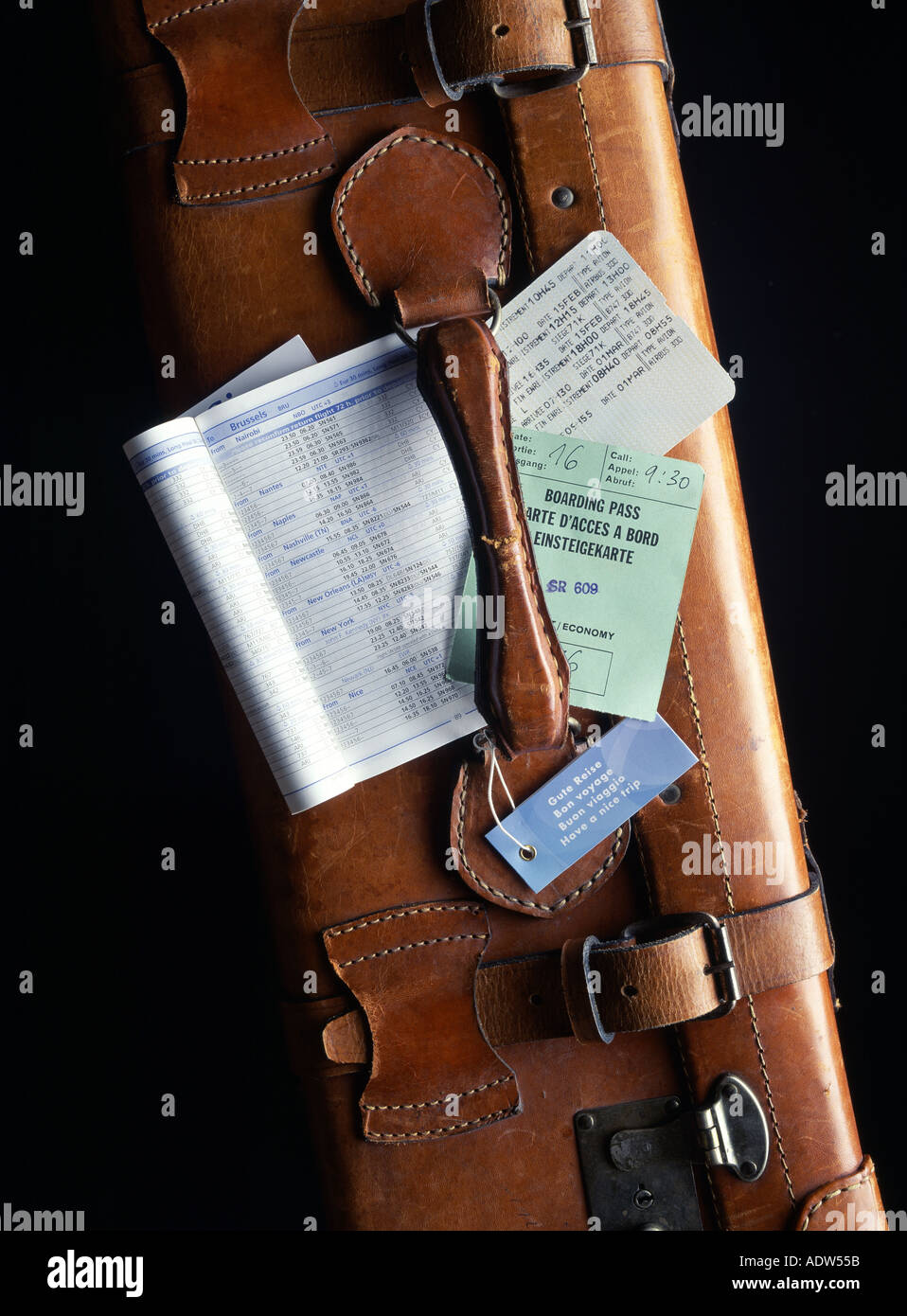AIRLINE TIMETABLE WITH PASSENGER TICKET AND BOARDING PASS ON TOP OF A LEATHER SUITCASE Stock Photo