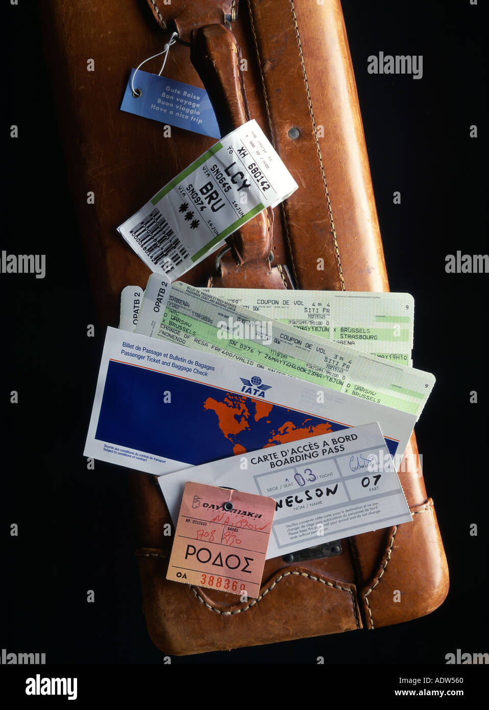 AIRLINE PASSENGER TICKETS, BOARDING PASSES, CHECKED LUGGAGE TAB, BAGGAGE LABELS ON TOP OF A LEATHER SUITCASE Stock Photo